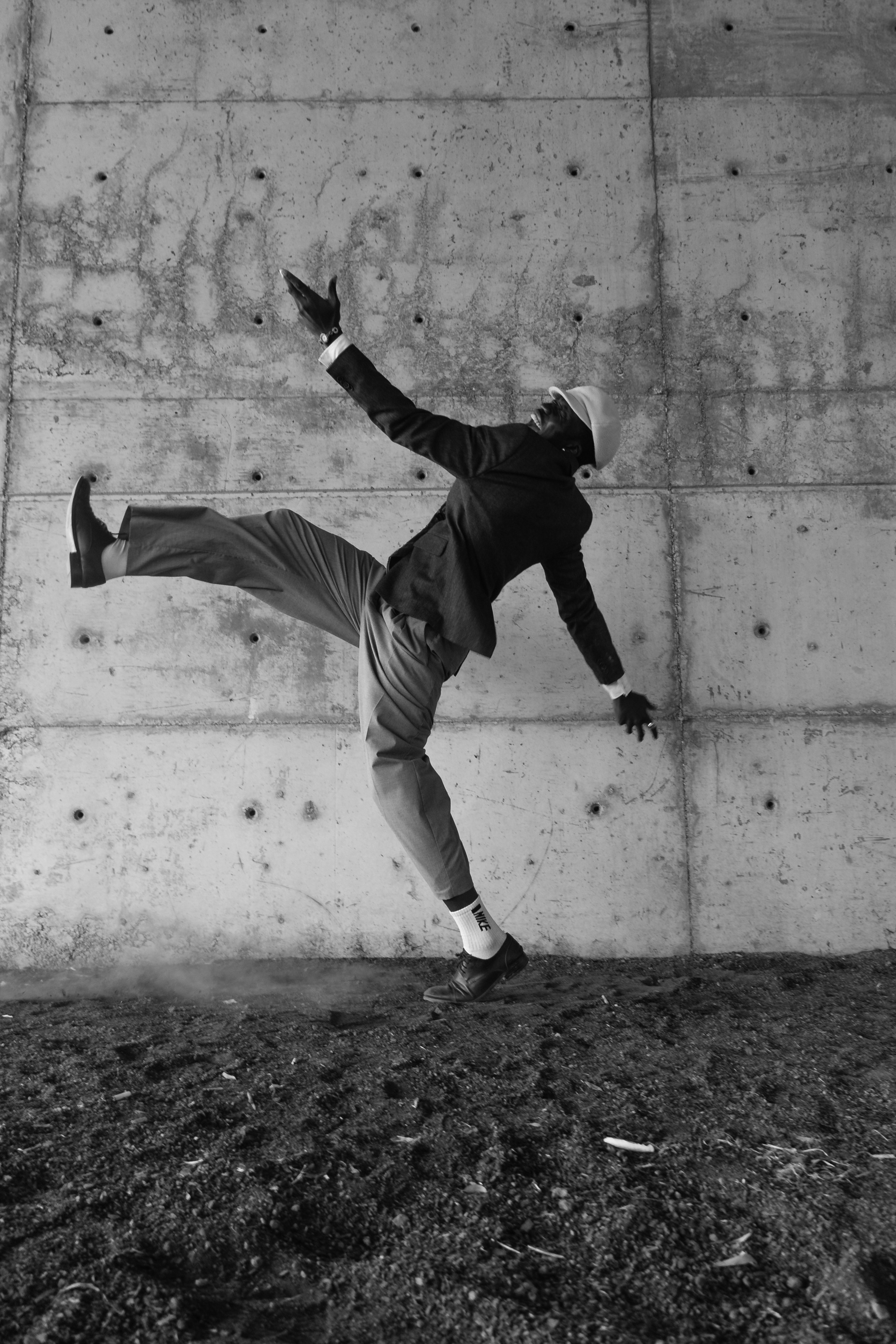 Un homme en costume et casque danse contre un mur de béton