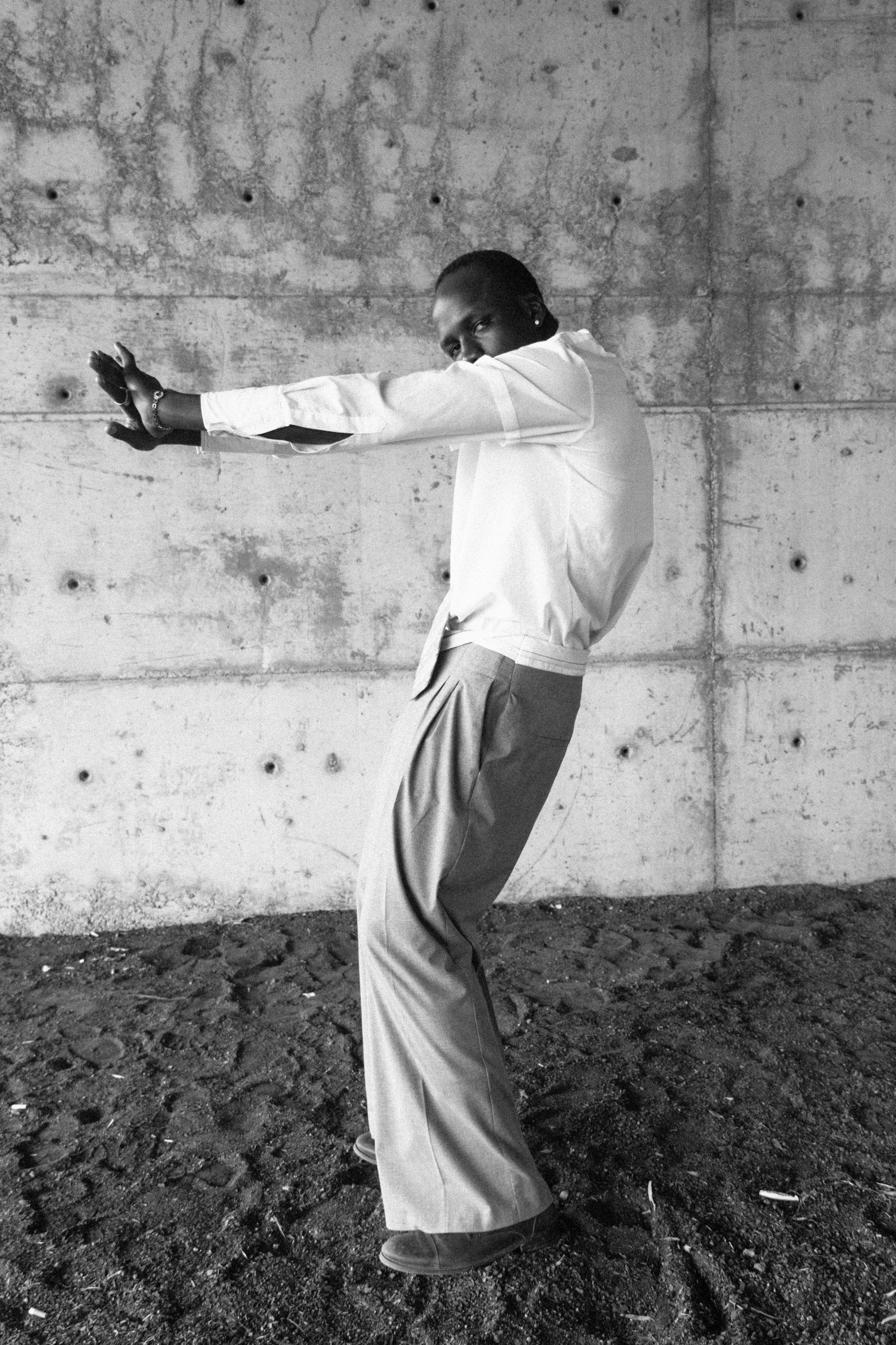 Homme en chemise blanche appuyé contre un mur en béton