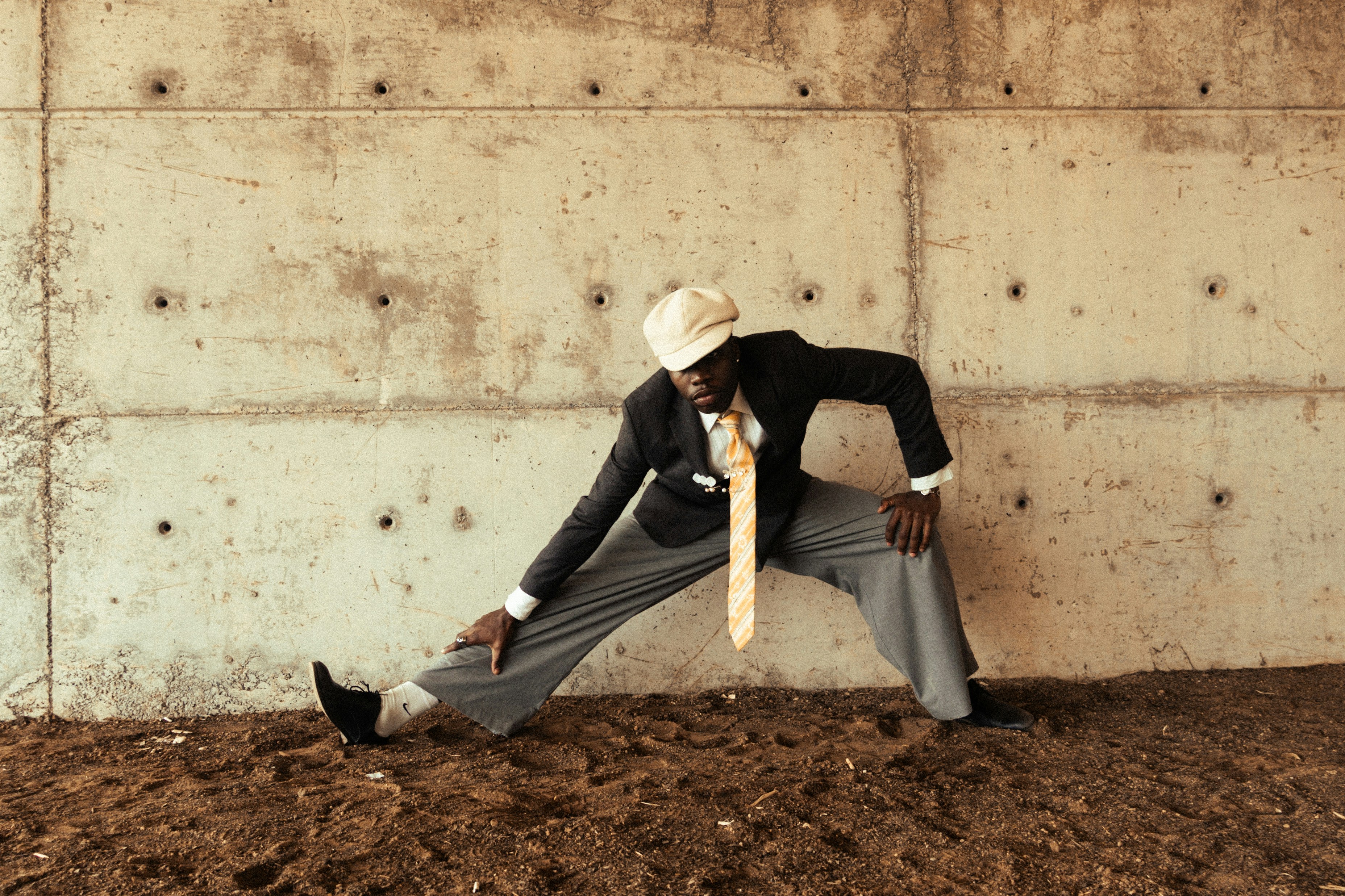 Homme en costume étiré contre un mur en béton