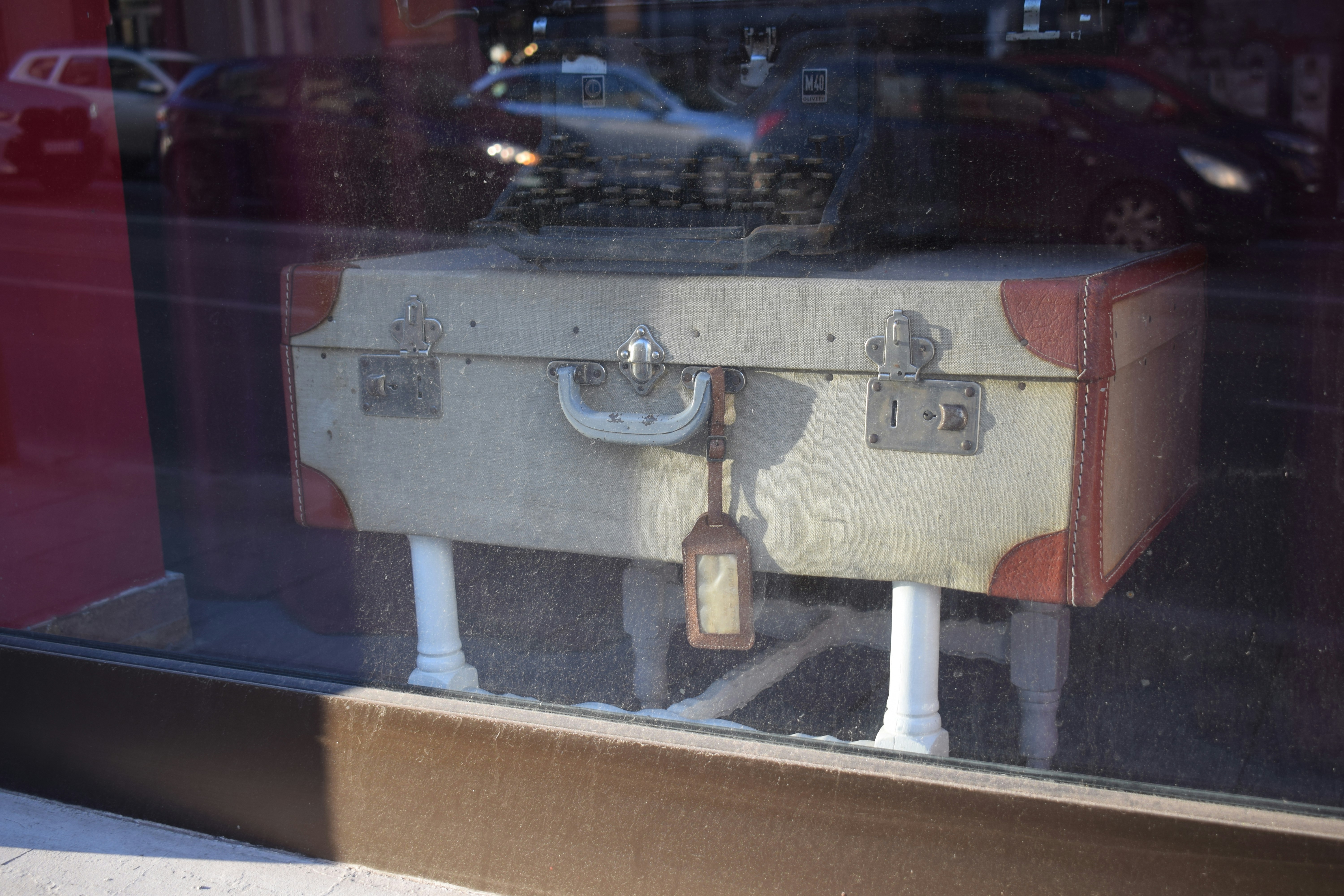 Vintage suitcase with tag on display.