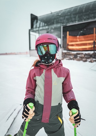Young skier in helmet and goggles on snowy slope.
