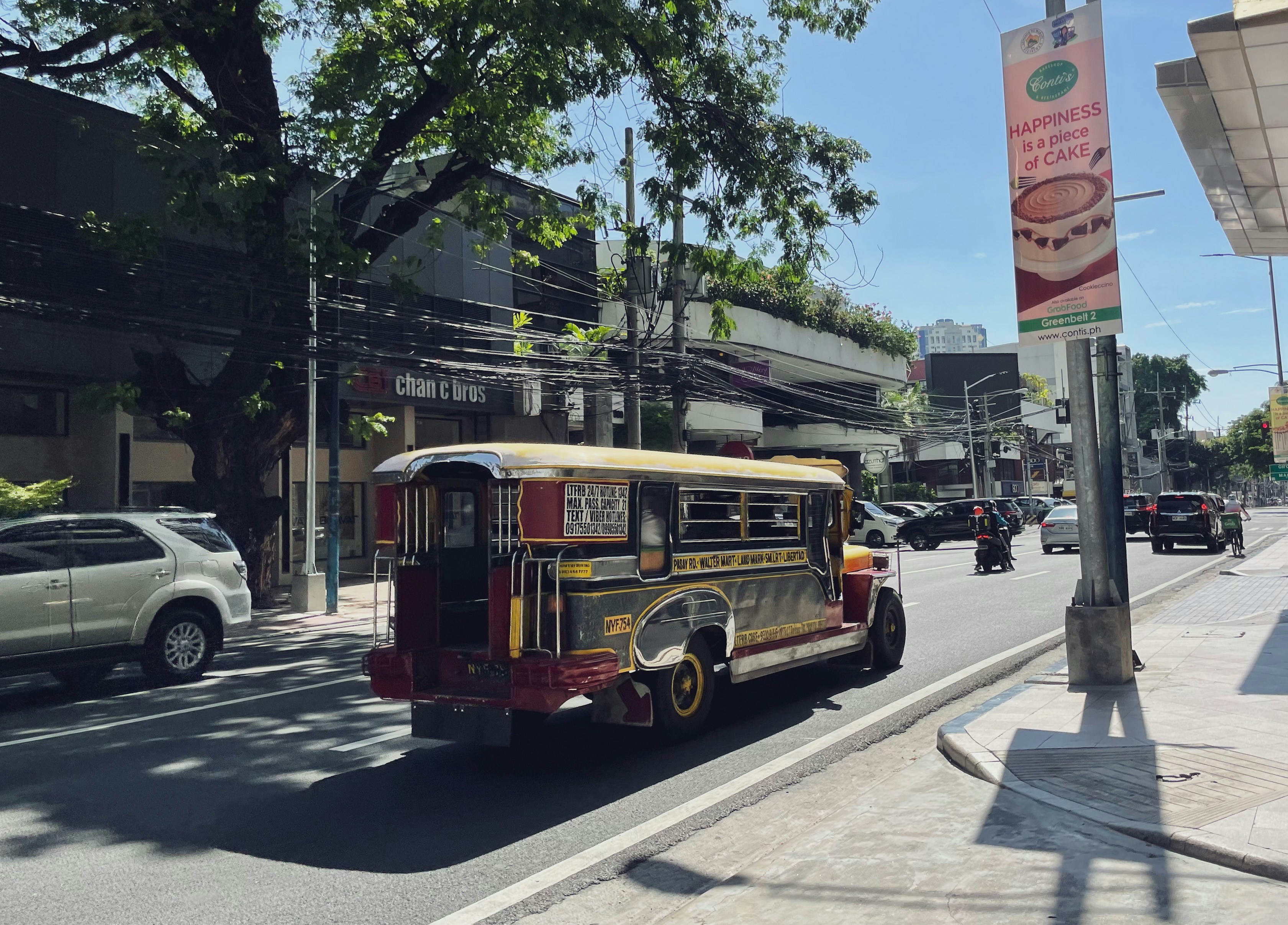 A colorful jeepney drives down a sunny street.