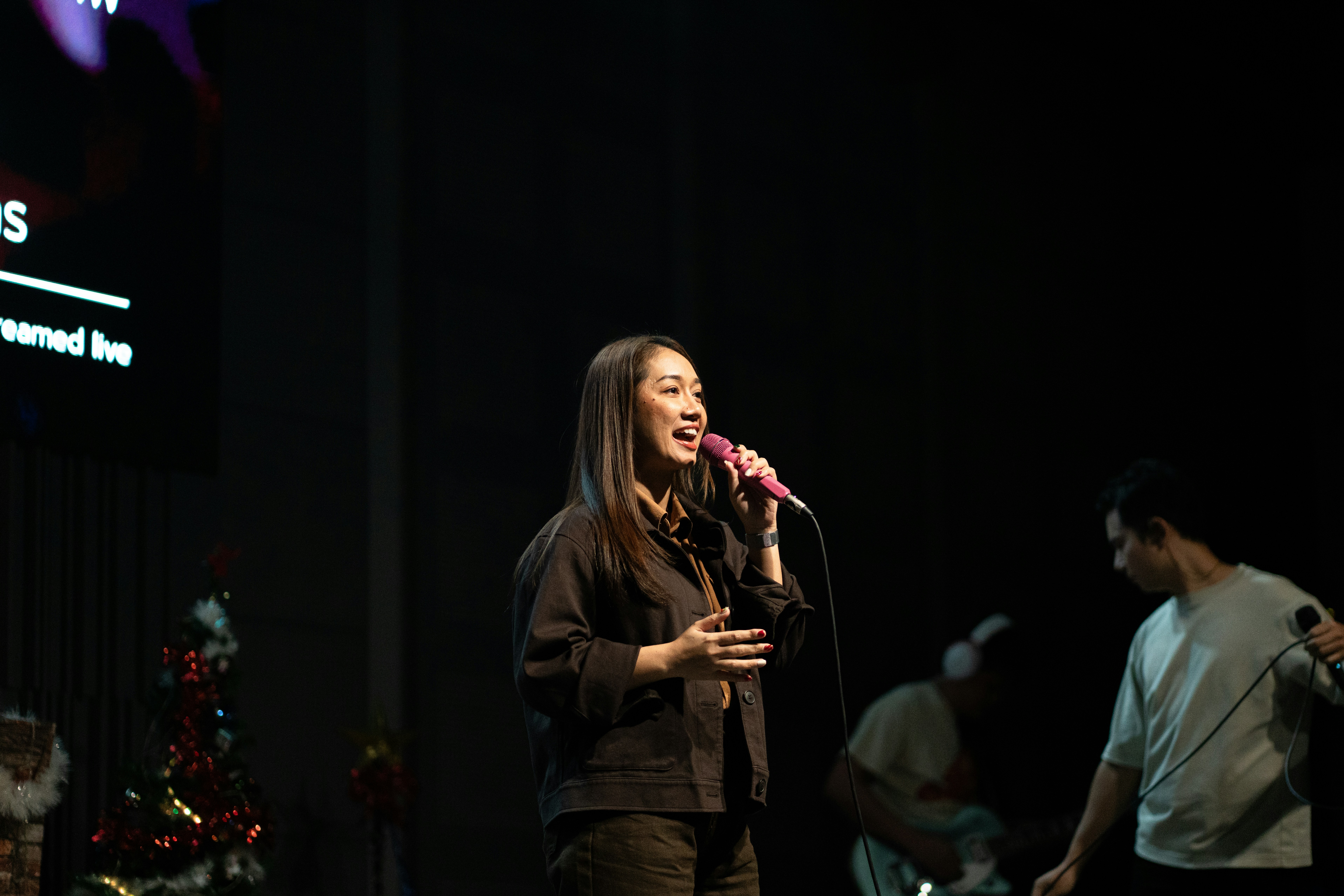 A woman sings into a microphone on stage.