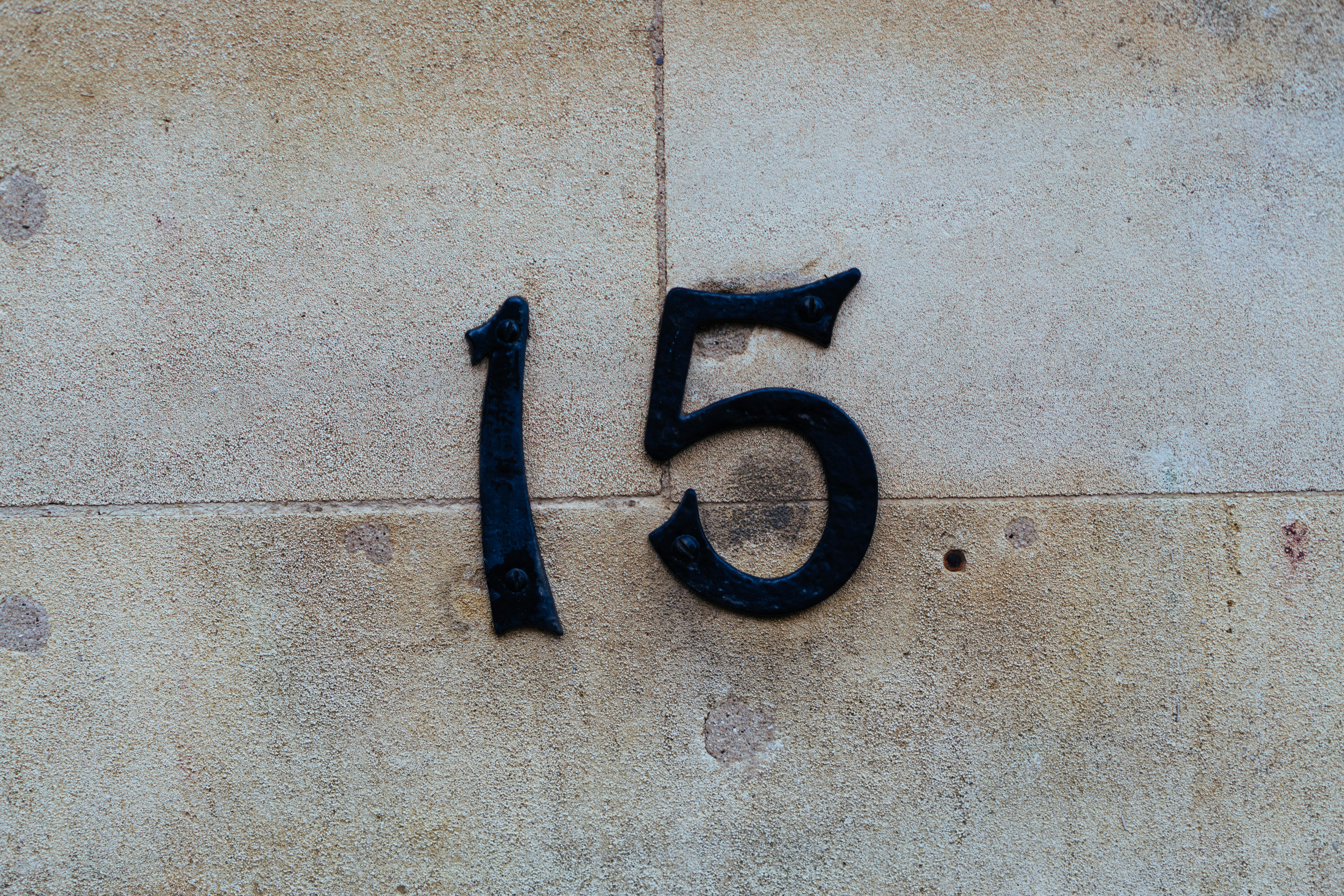 Black number 15 on a stone wall.