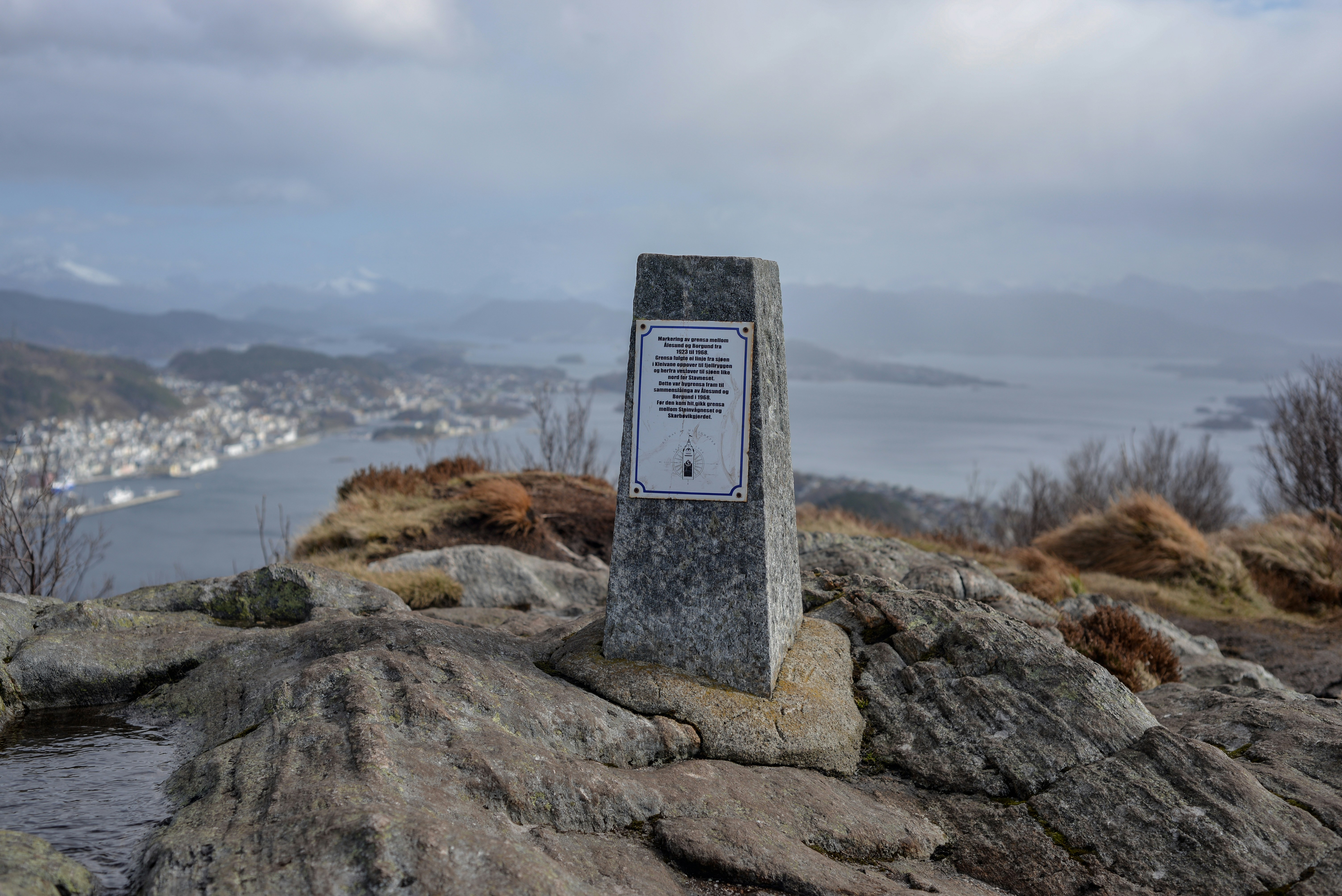 Stone monument on rocky hilltop overlooking a bay.