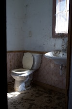 An old, dirty bathroom with a toilet and sink.