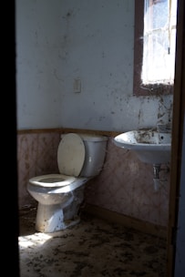An old, dirty bathroom with a toilet and sink.