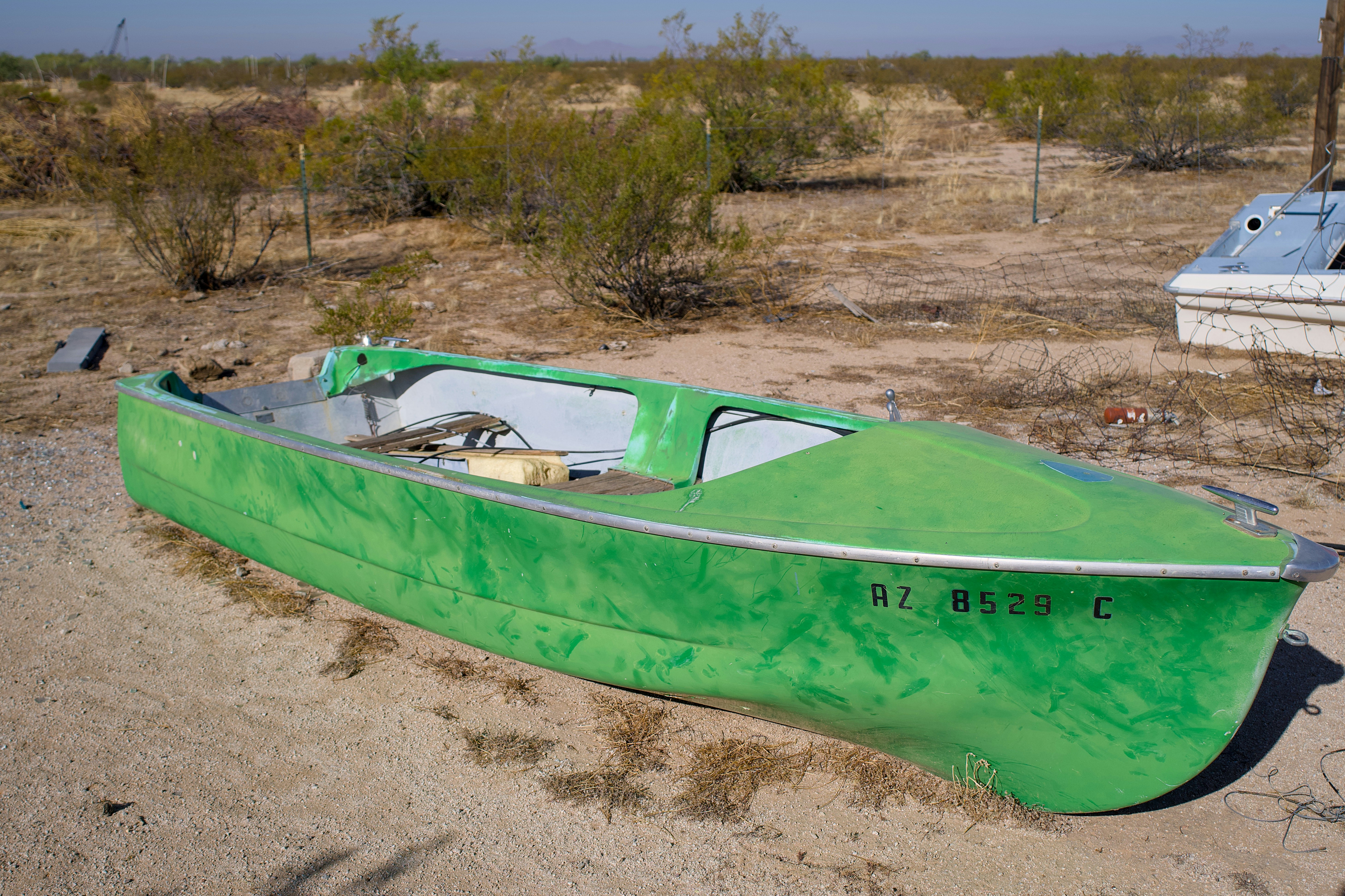 Un barco verde descansando sobre suelo arenoso.