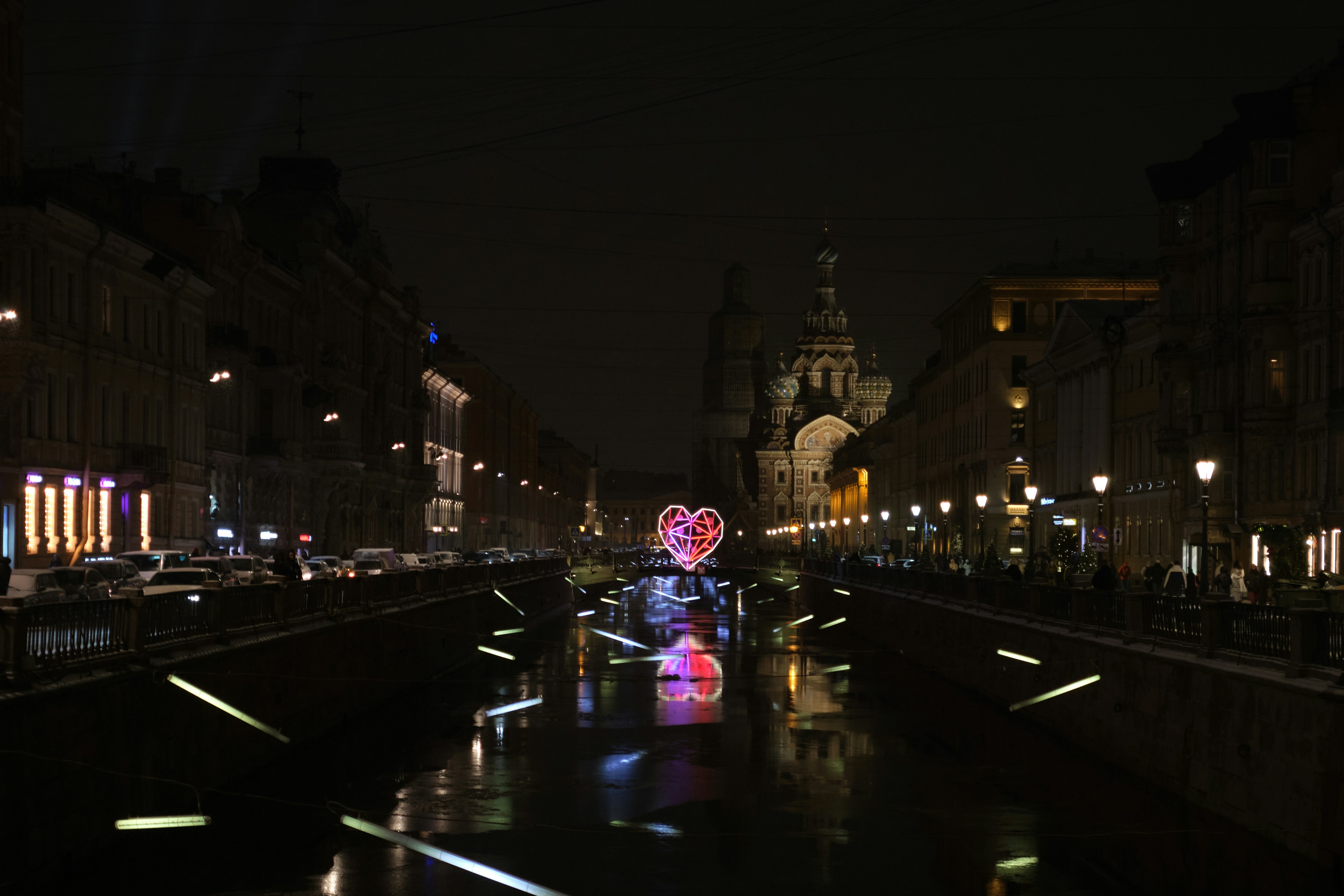 A glowing heart decoration on a canal at night.