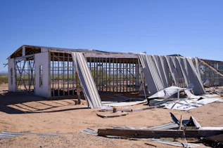 Damaged building with exposed framing and bent metal roofing.