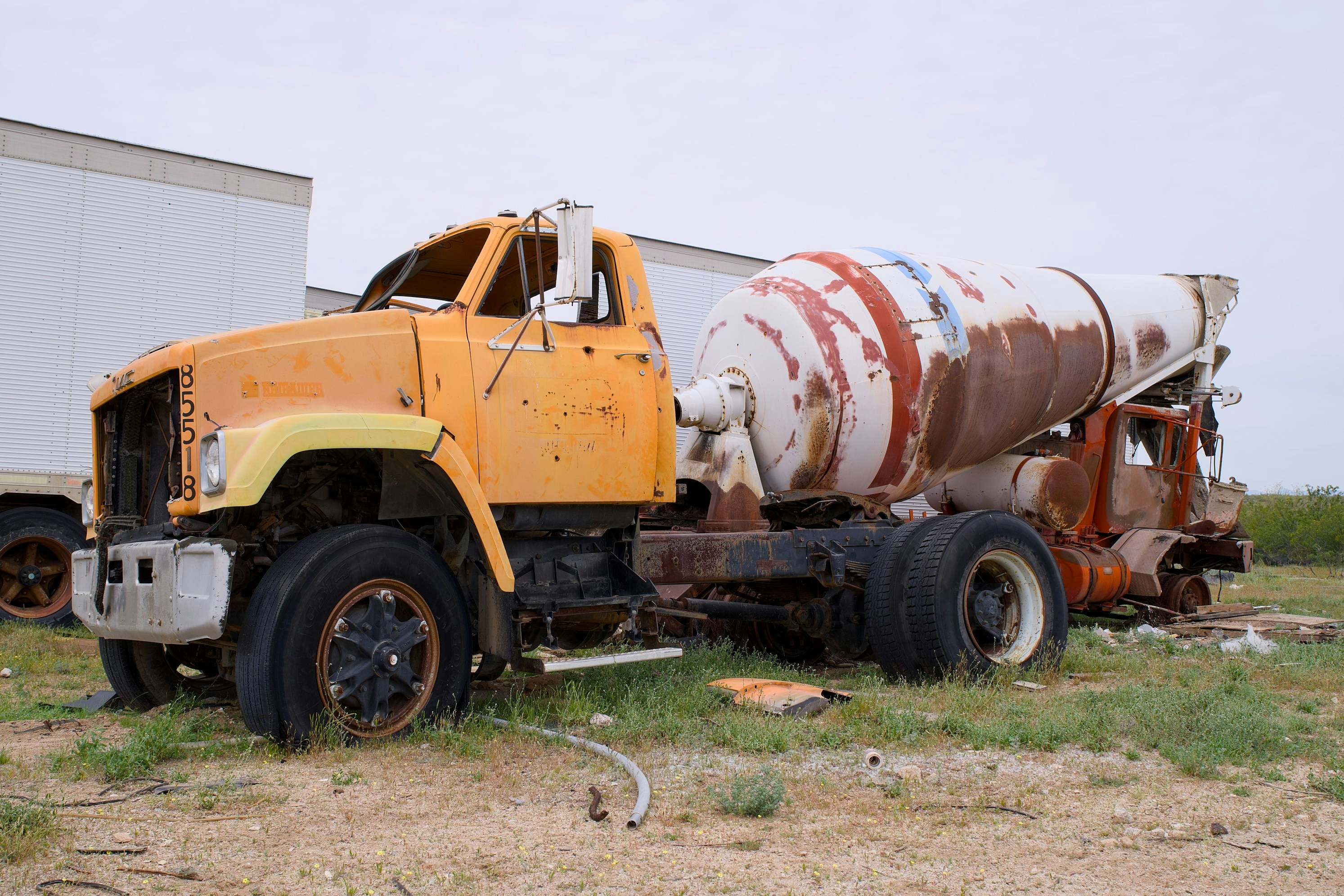An old, rusty cement mixer truck sits abandoned.