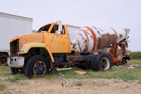 An old, rusty cement mixer truck sits abandoned.
