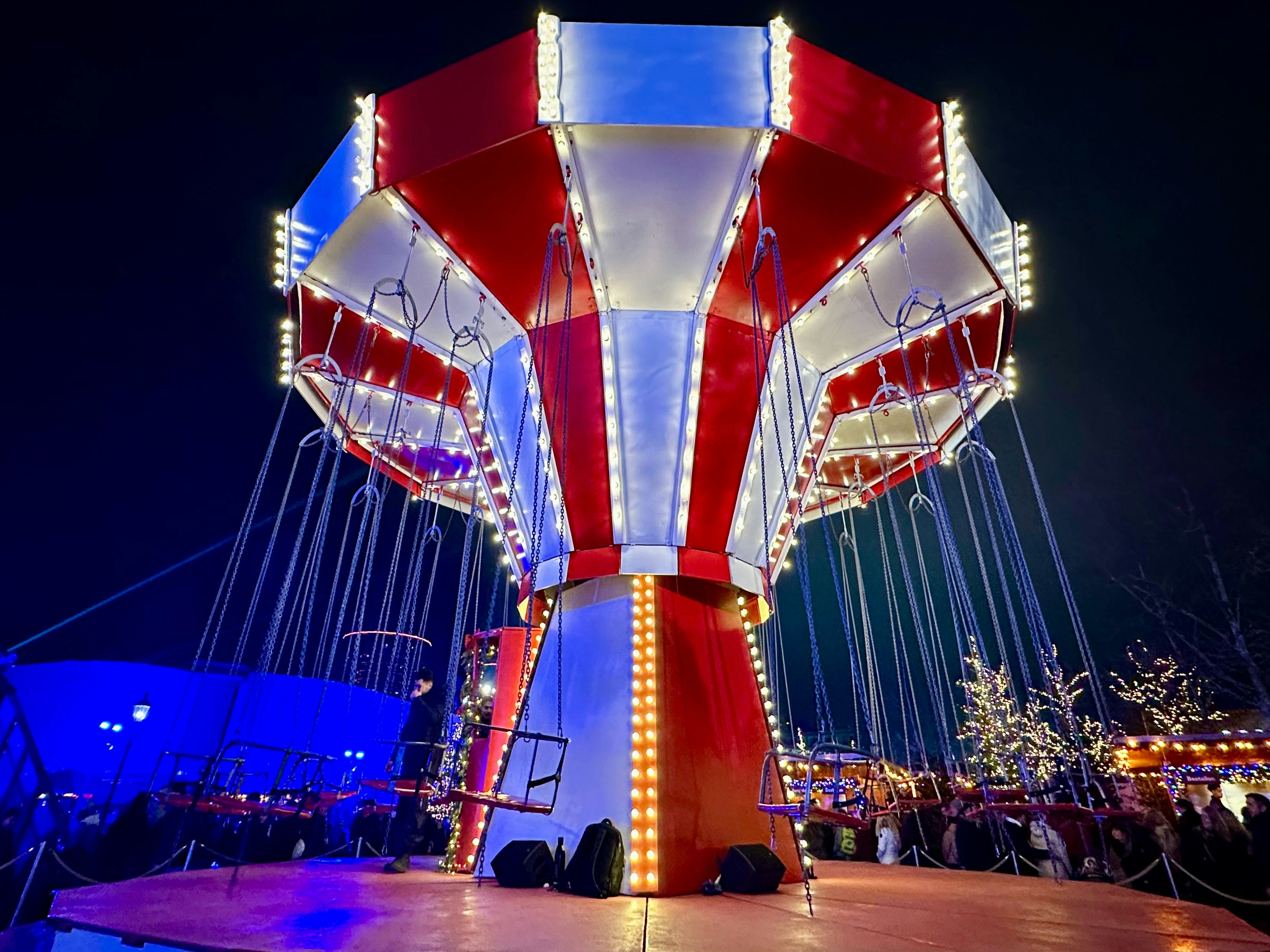 A brightly lit carnival swing ride at night