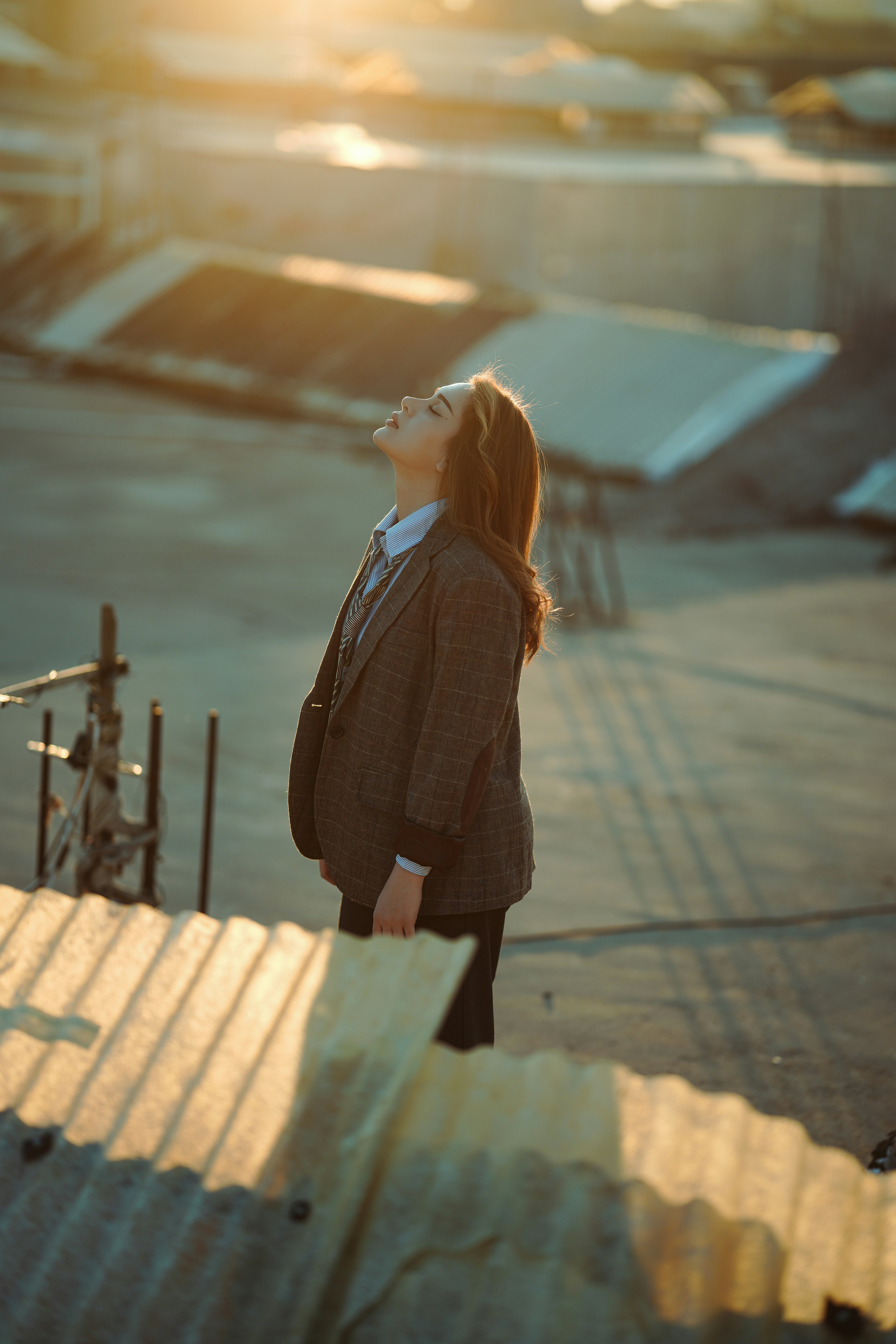 Woman looking up at the sun on a rooftop.