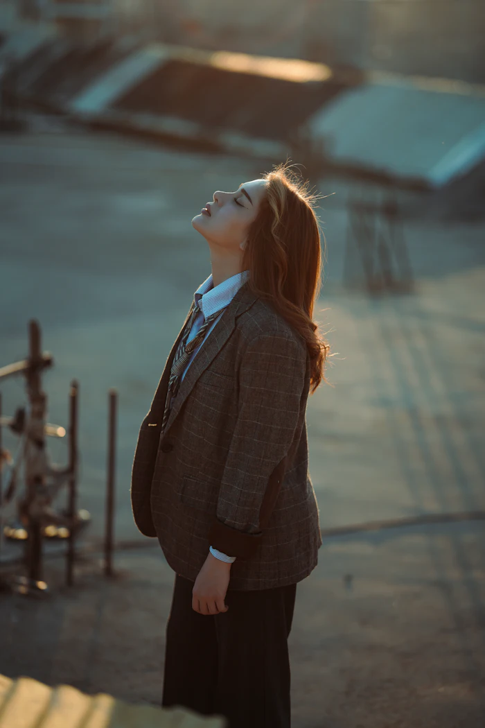 A recent graduate standing outside, looking ahead into the light