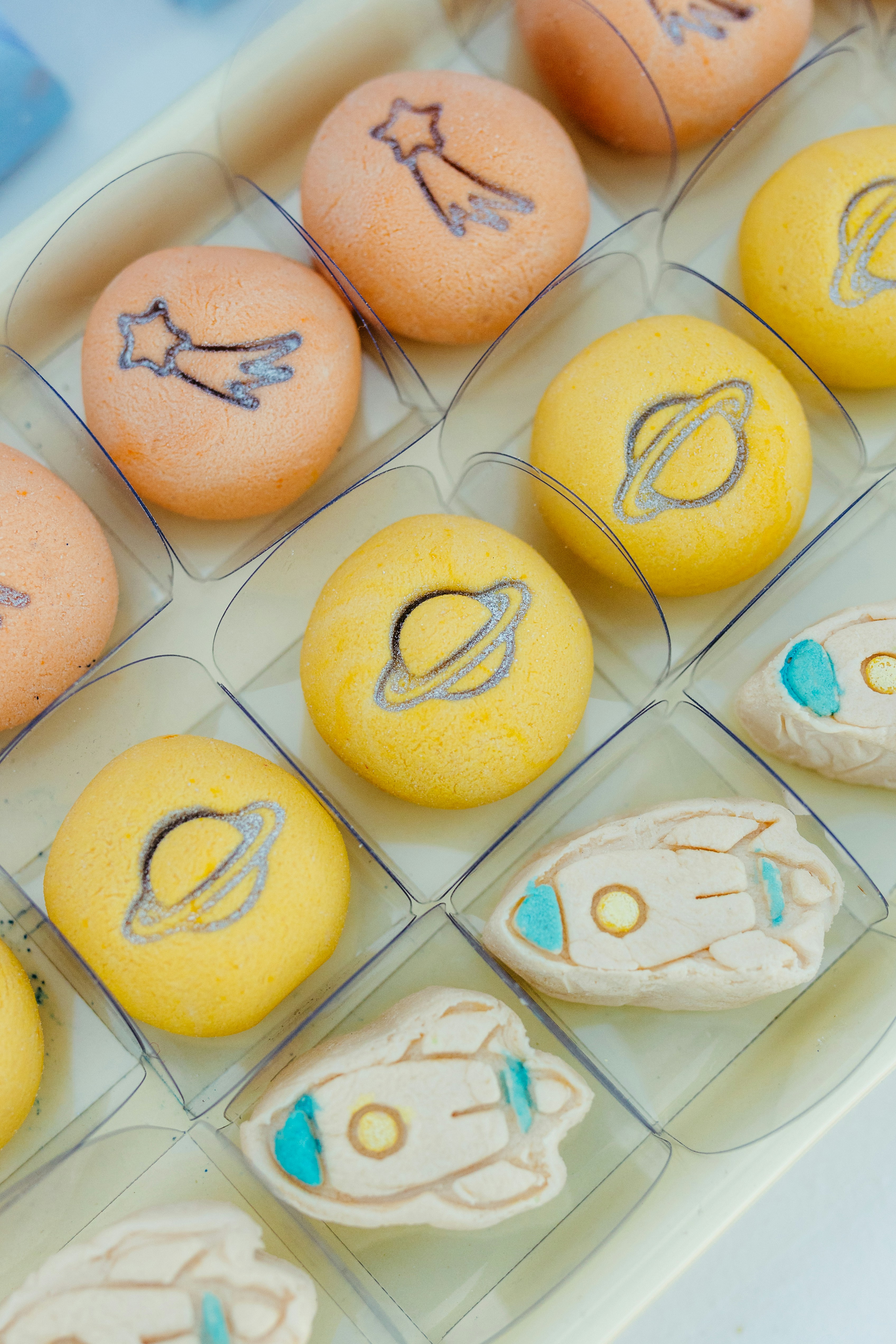 Round orange and yellow pastries with space designs.