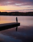 Person standing on a dock at sunset