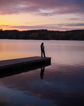 Person standing on a dock at sunset
