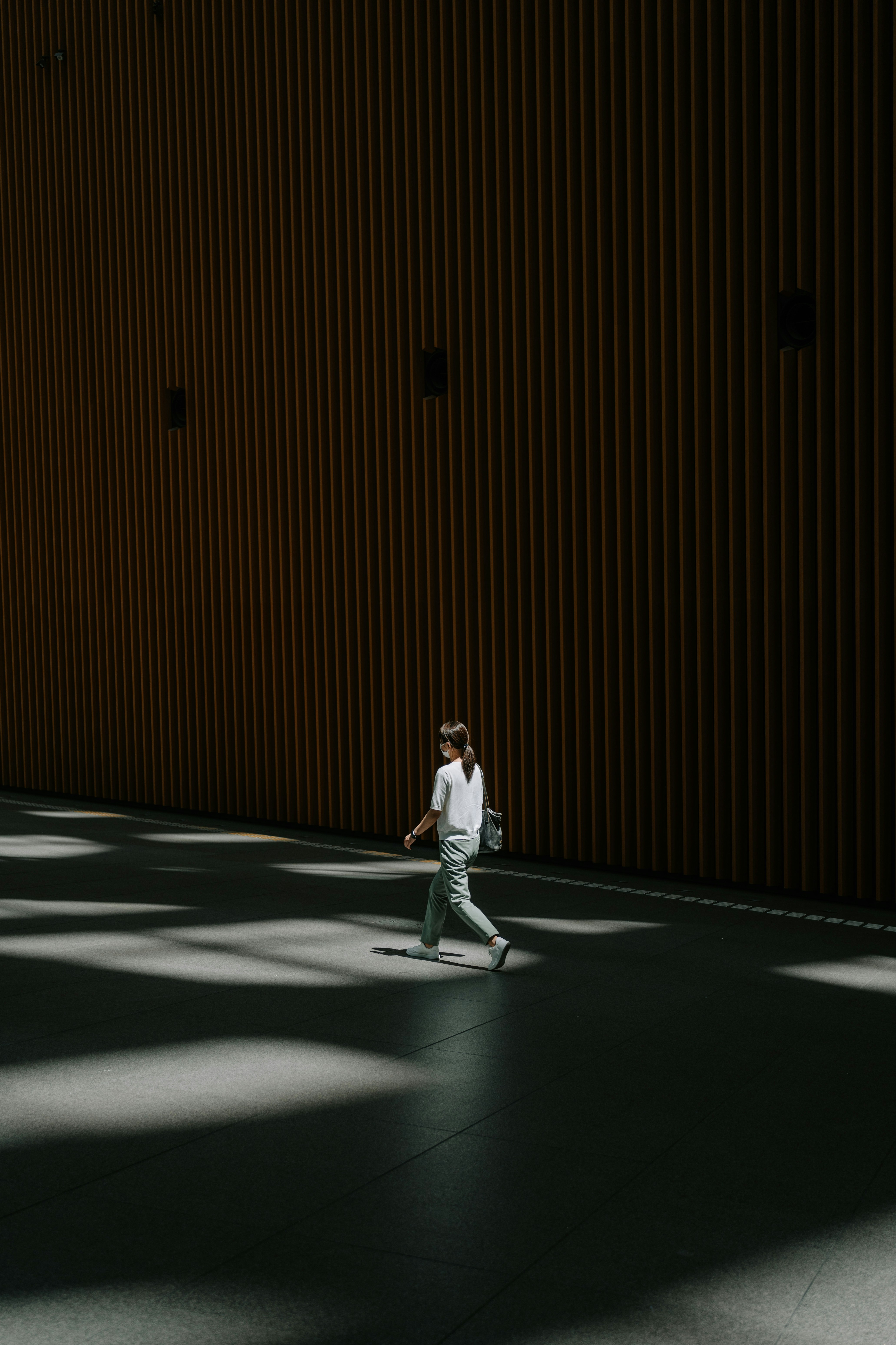 A person walks in a sunlit modern hallway.