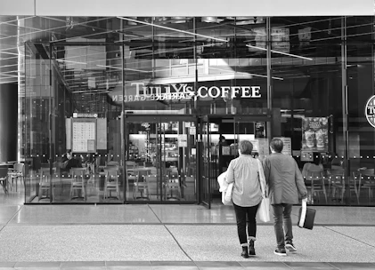 Two people walk towards a tully's coffee shop entrance.