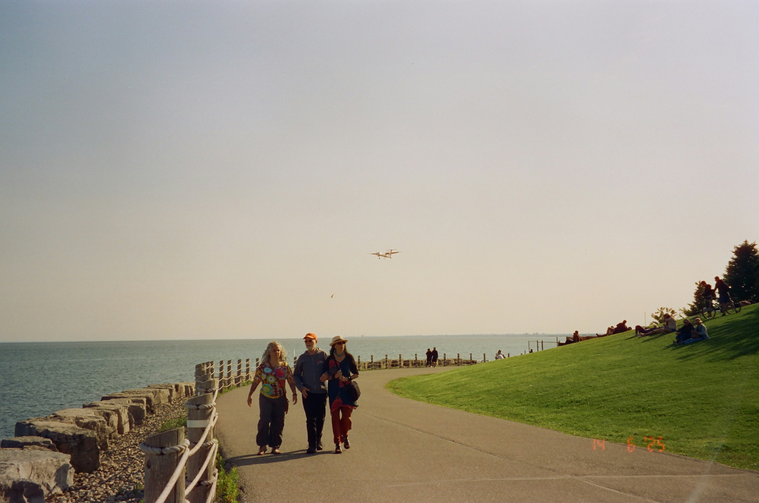 Three people walk along a seaside path.