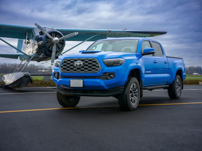 Blue pickup truck parked next to an airplane.