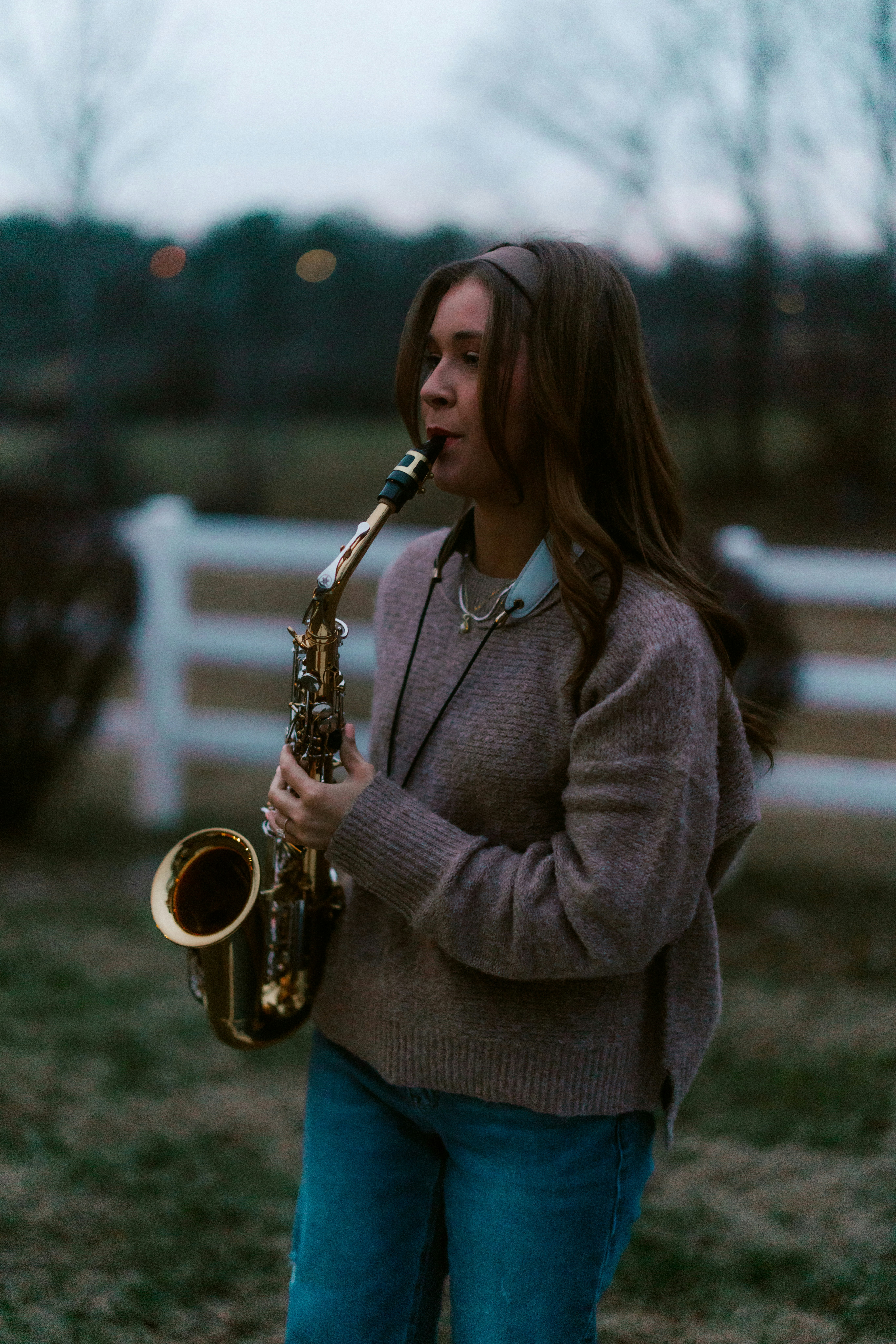 Young woman playing saxophone outdoors at dusk