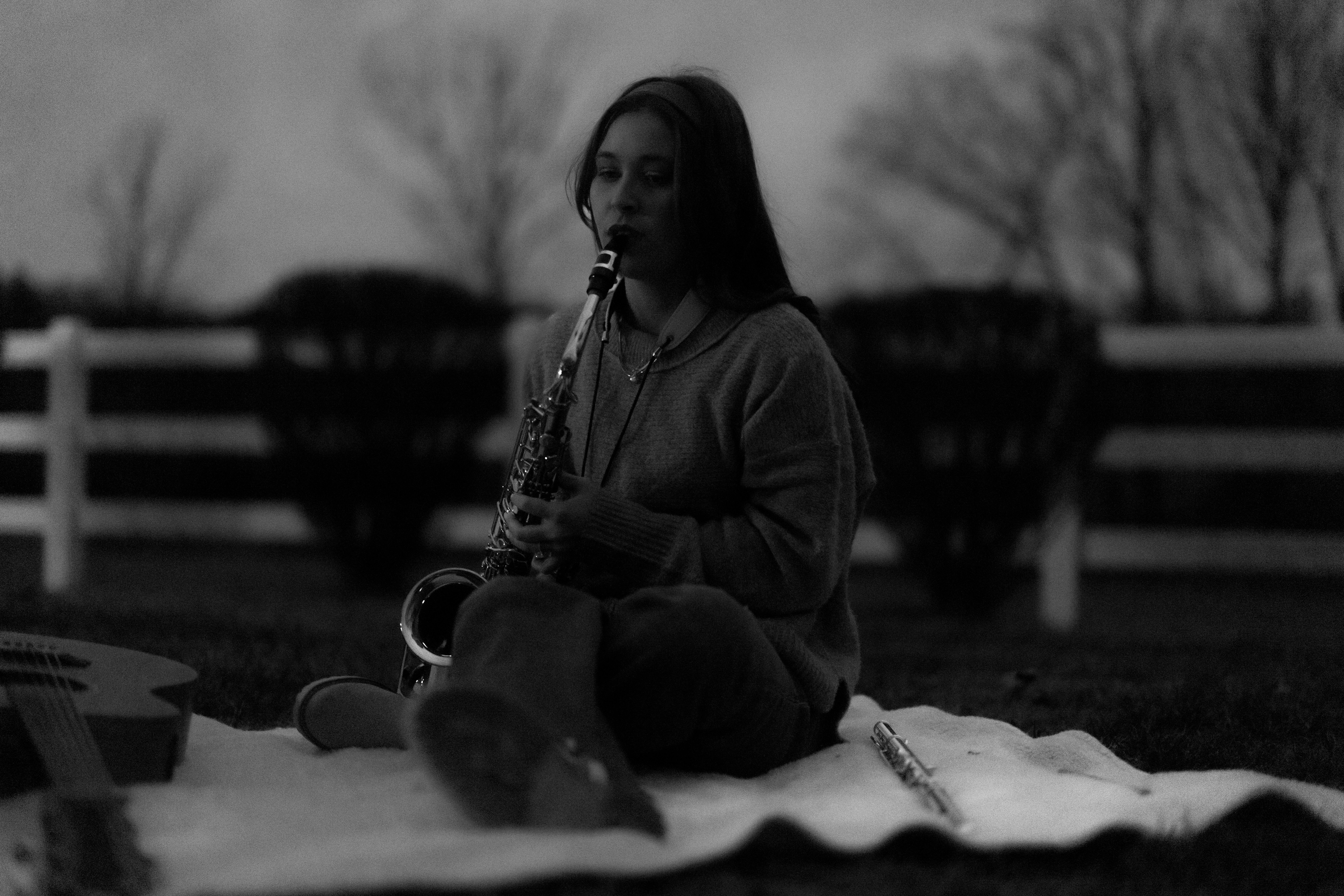 Young woman playing saxophone outdoors at dusk