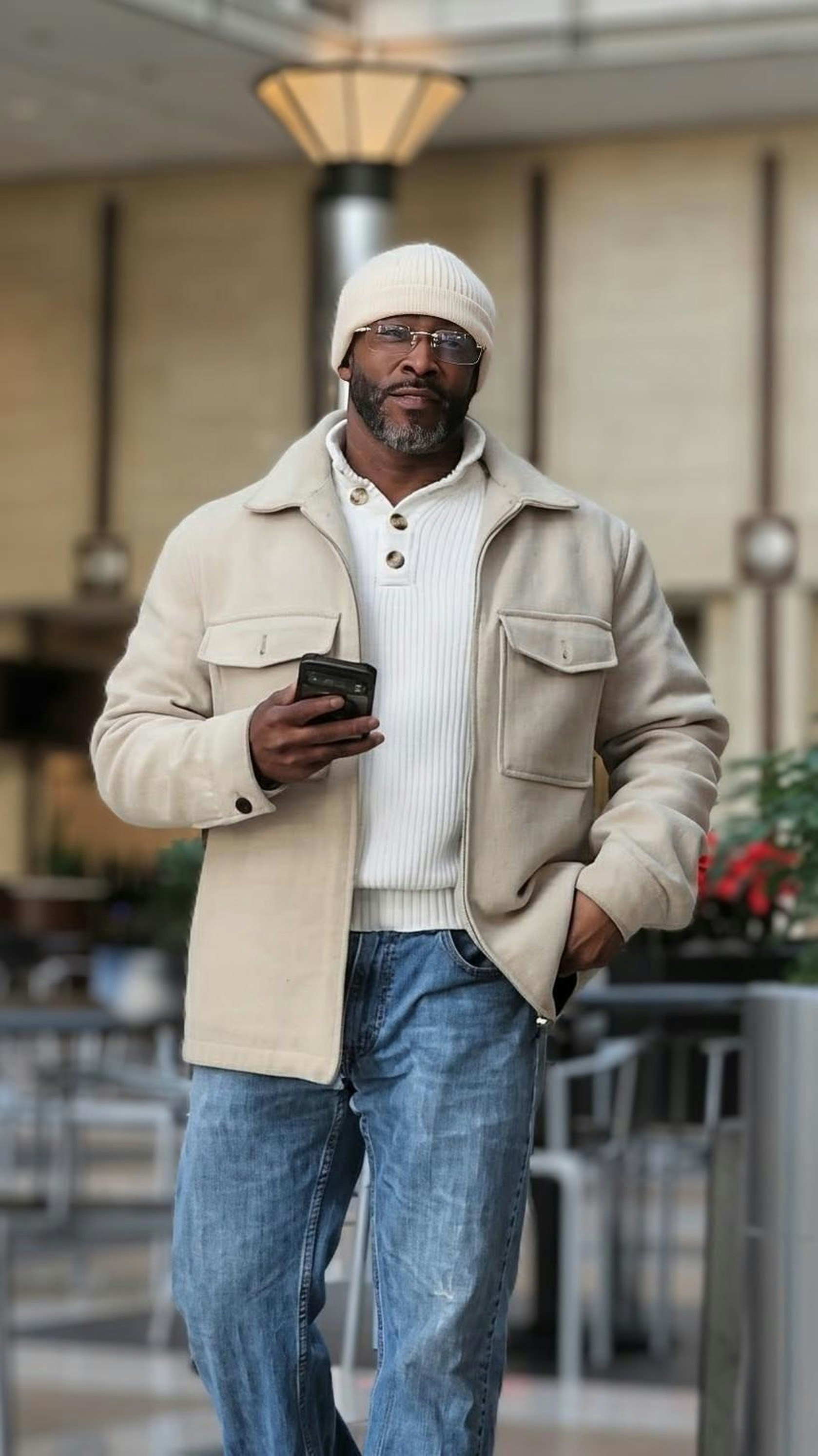Man in beige jacket and jeans holding phone