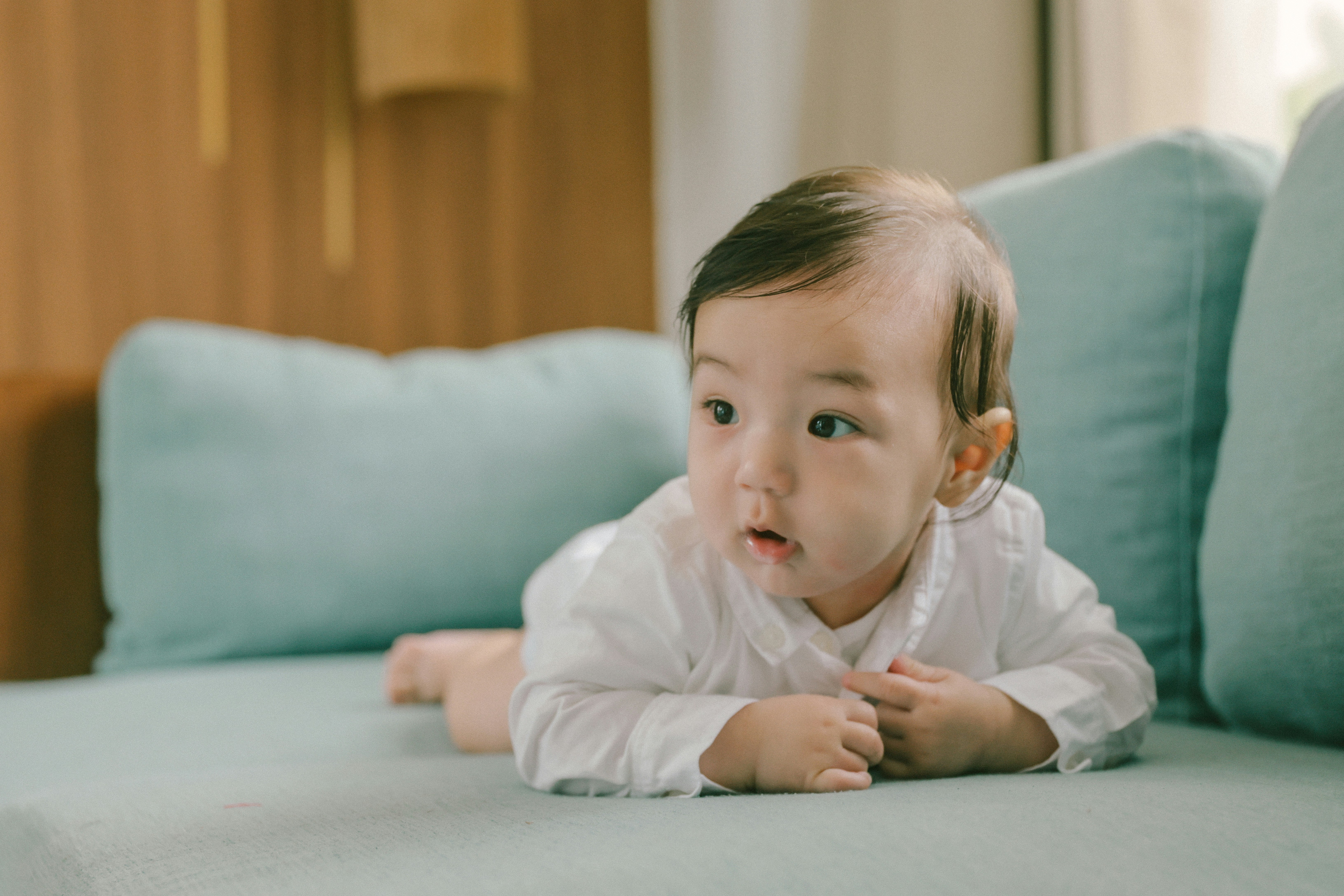 Baby lying on a couch with teal cushions