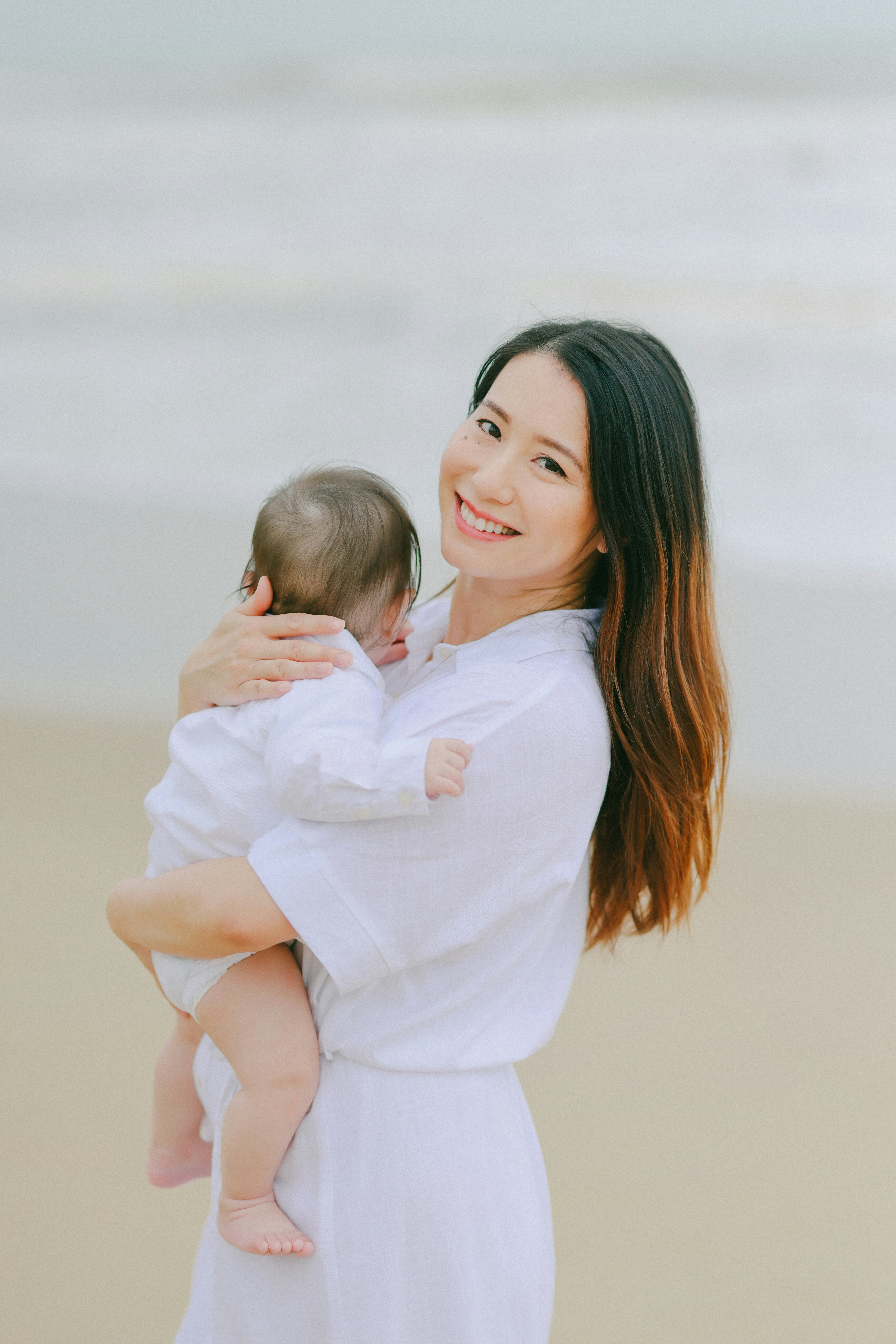 Mother holding her baby on the beach