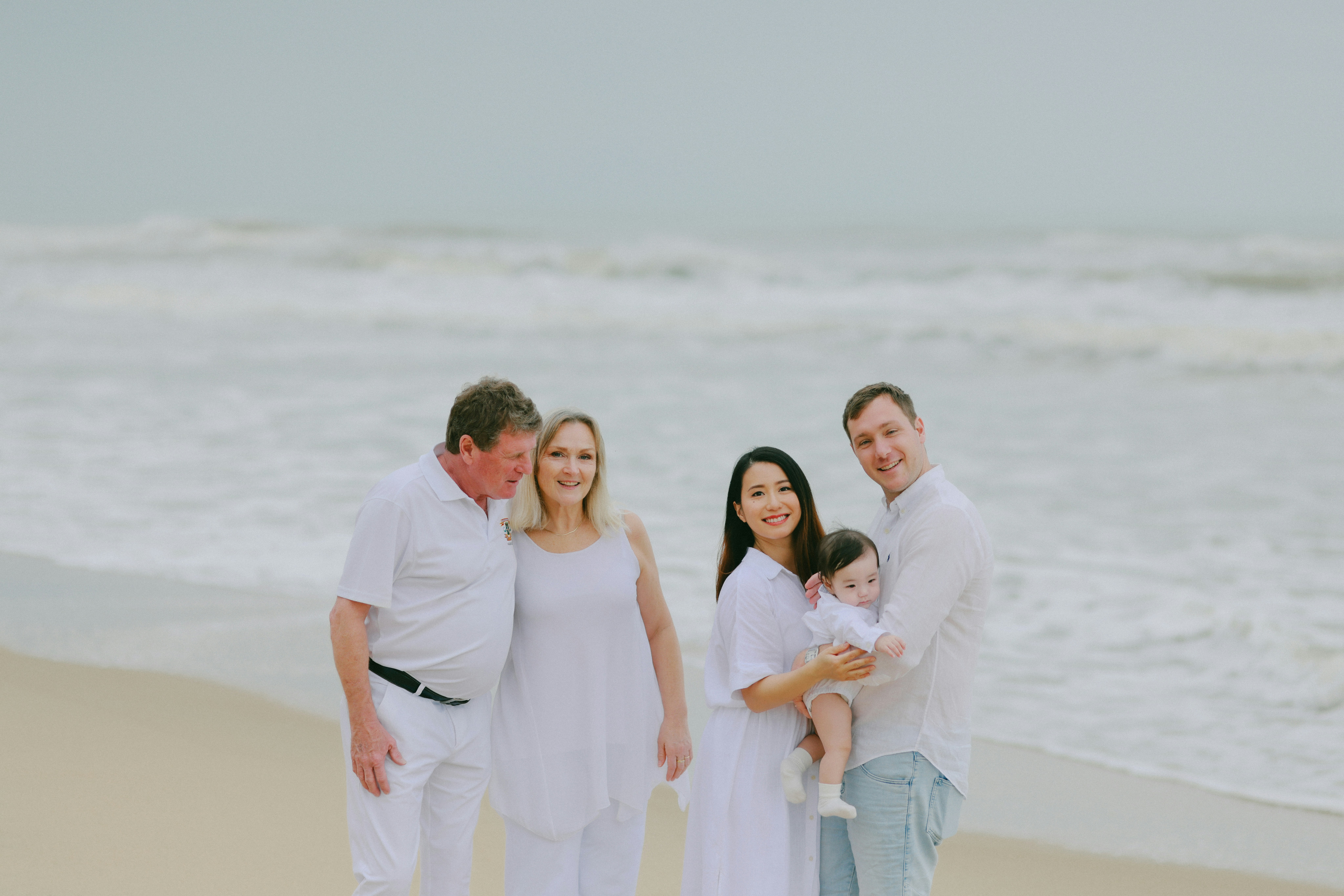 Familie posiert an einem Strand mit Meer-Hintergrund