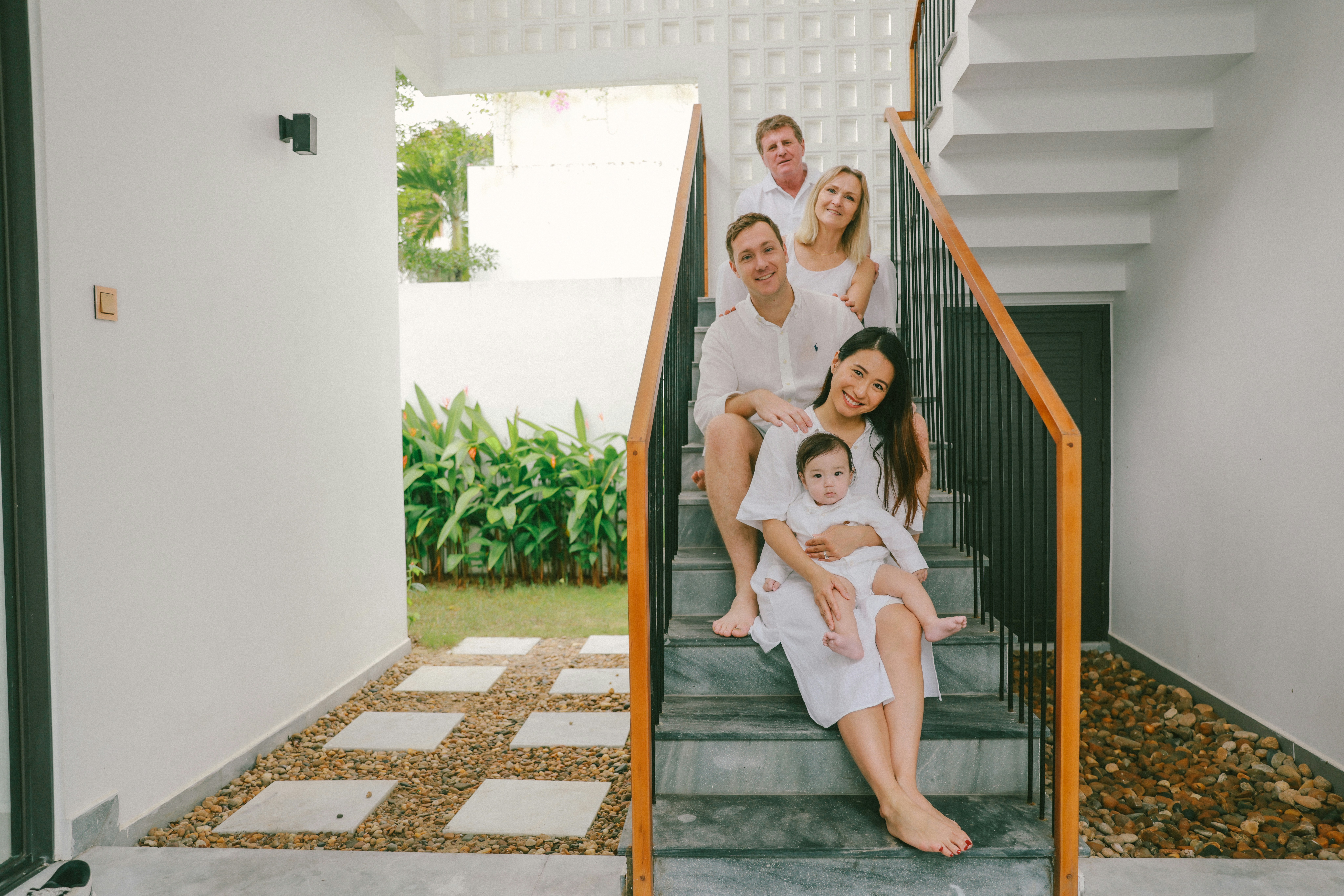 Family posing on stairs in white outfits.