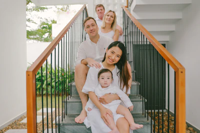 Family posing on stairs wearing white outfits.