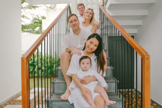 Family posing on stairs wearing white outfits.