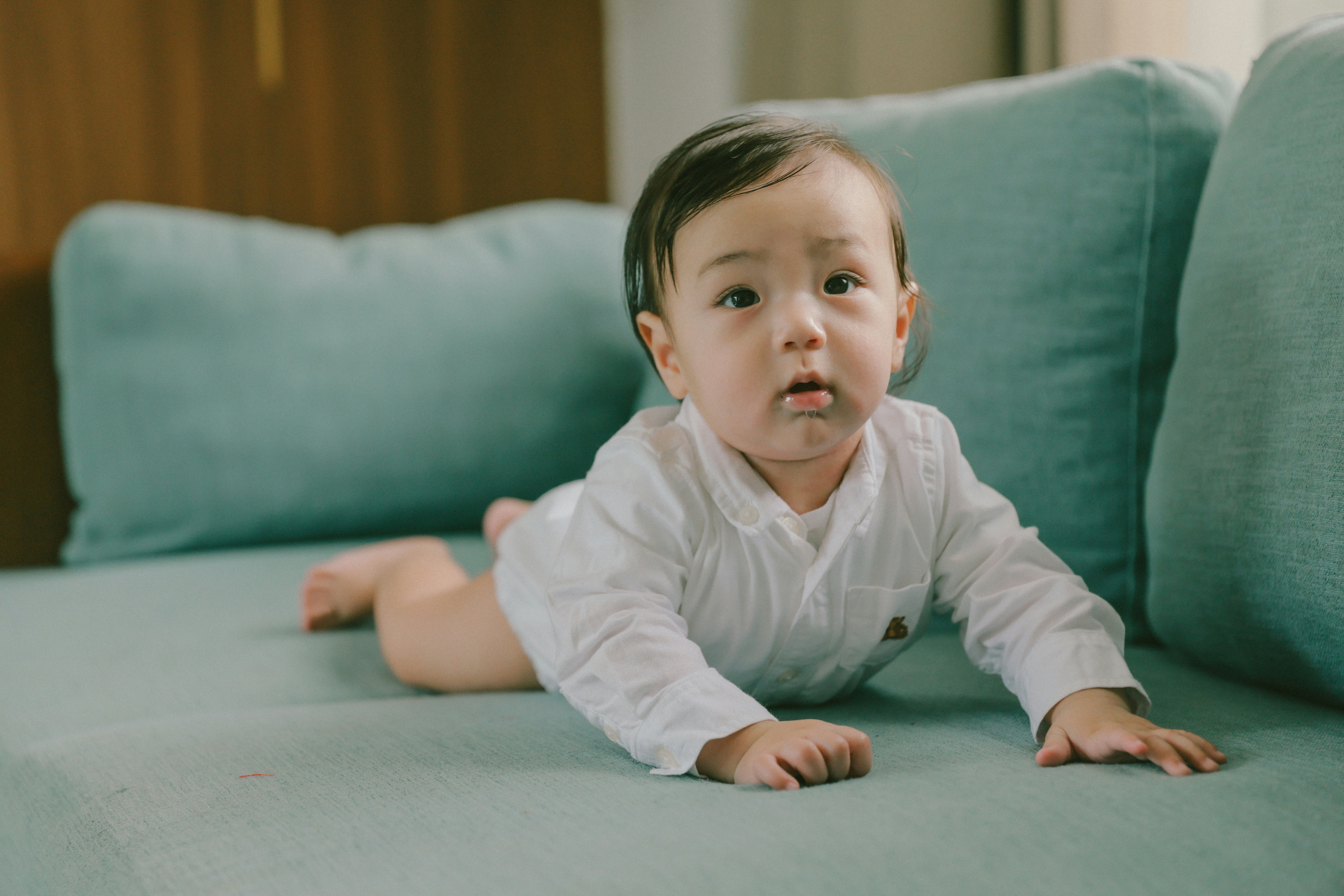 Baby crawling on a teal couch