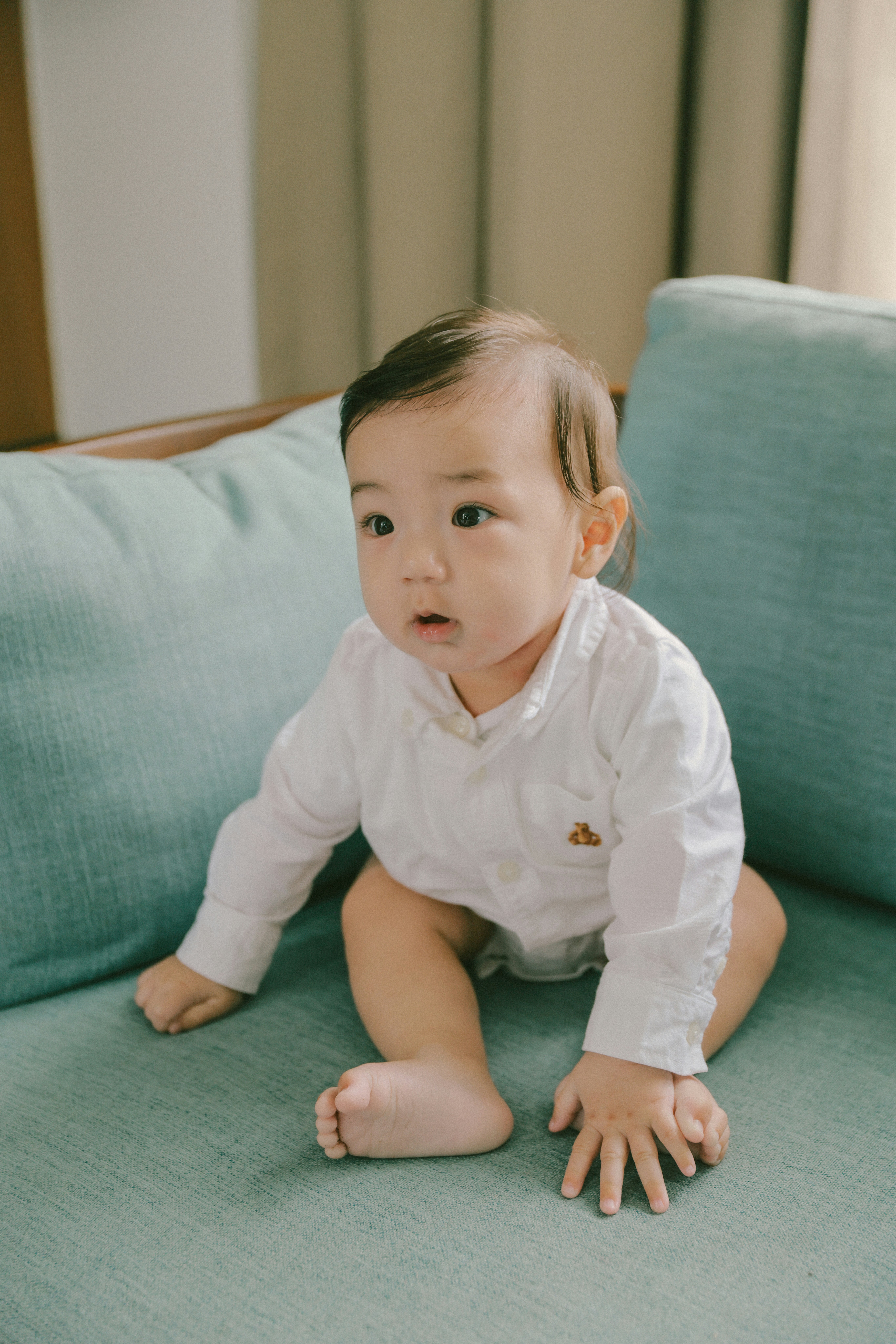 A baby in a white shirt sitting on a couch.