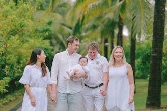 Family walking together on a path with palm trees.