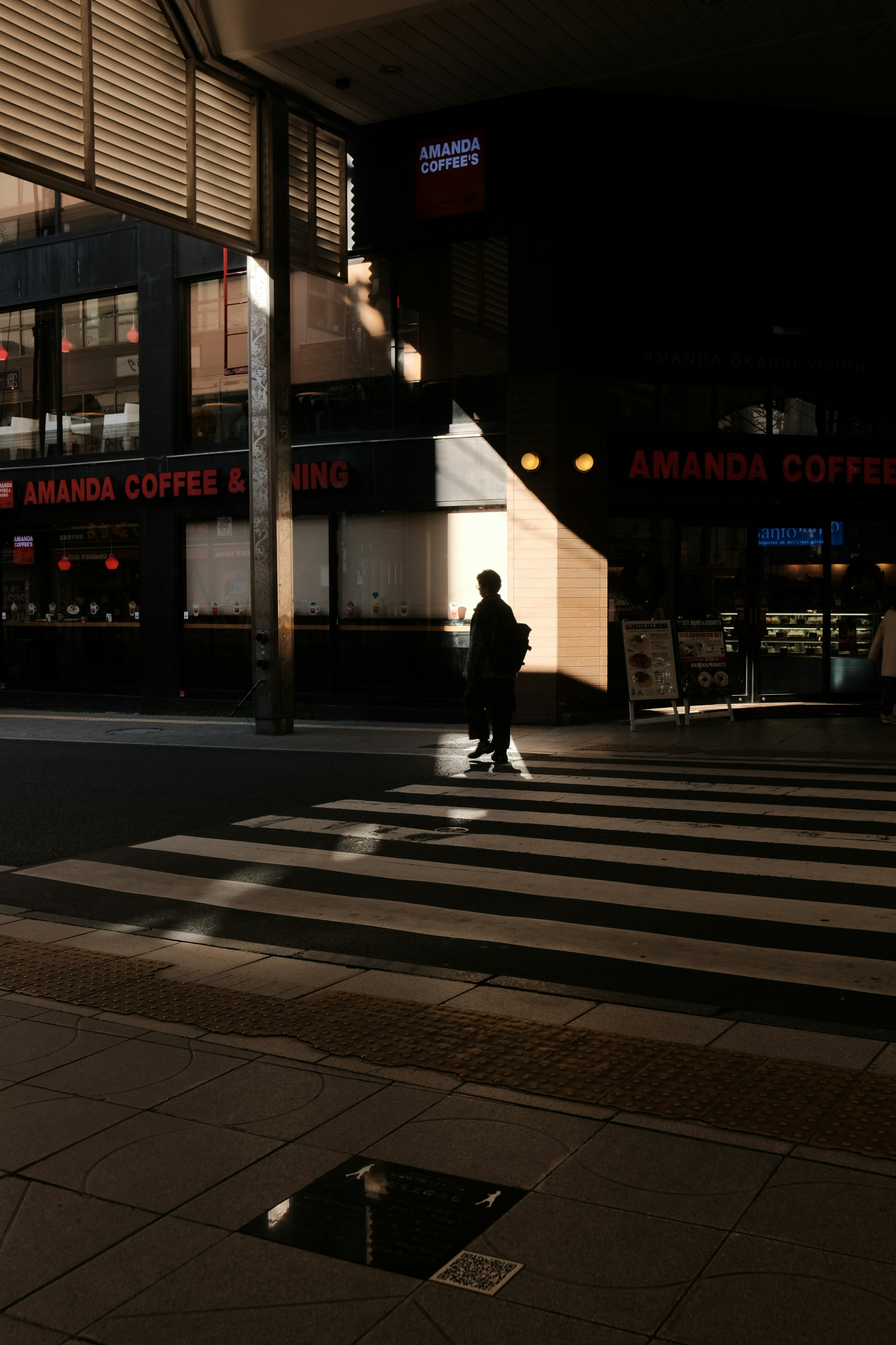 Person crossing street at night with shadows.