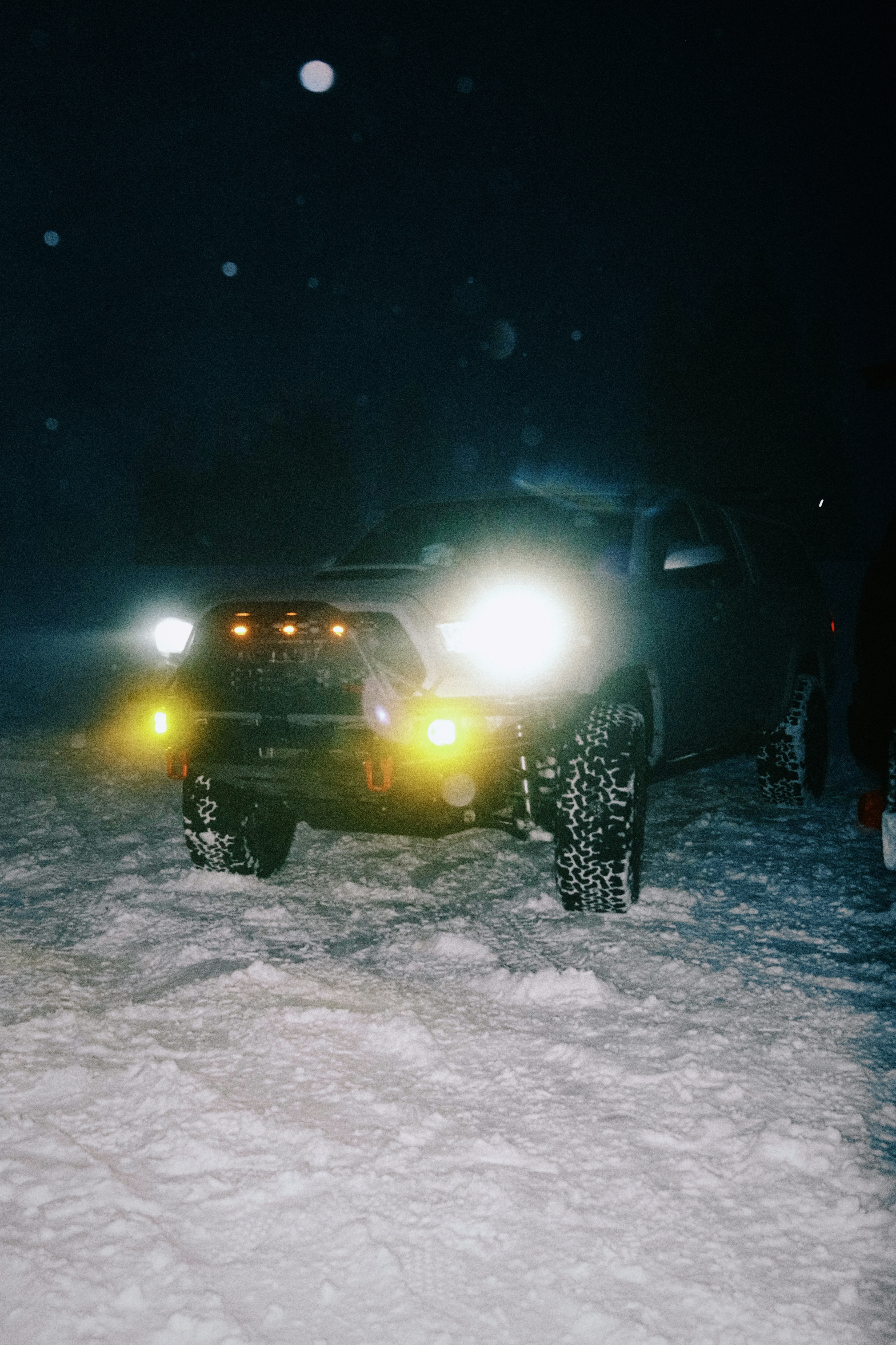 Truck driving through snow at night