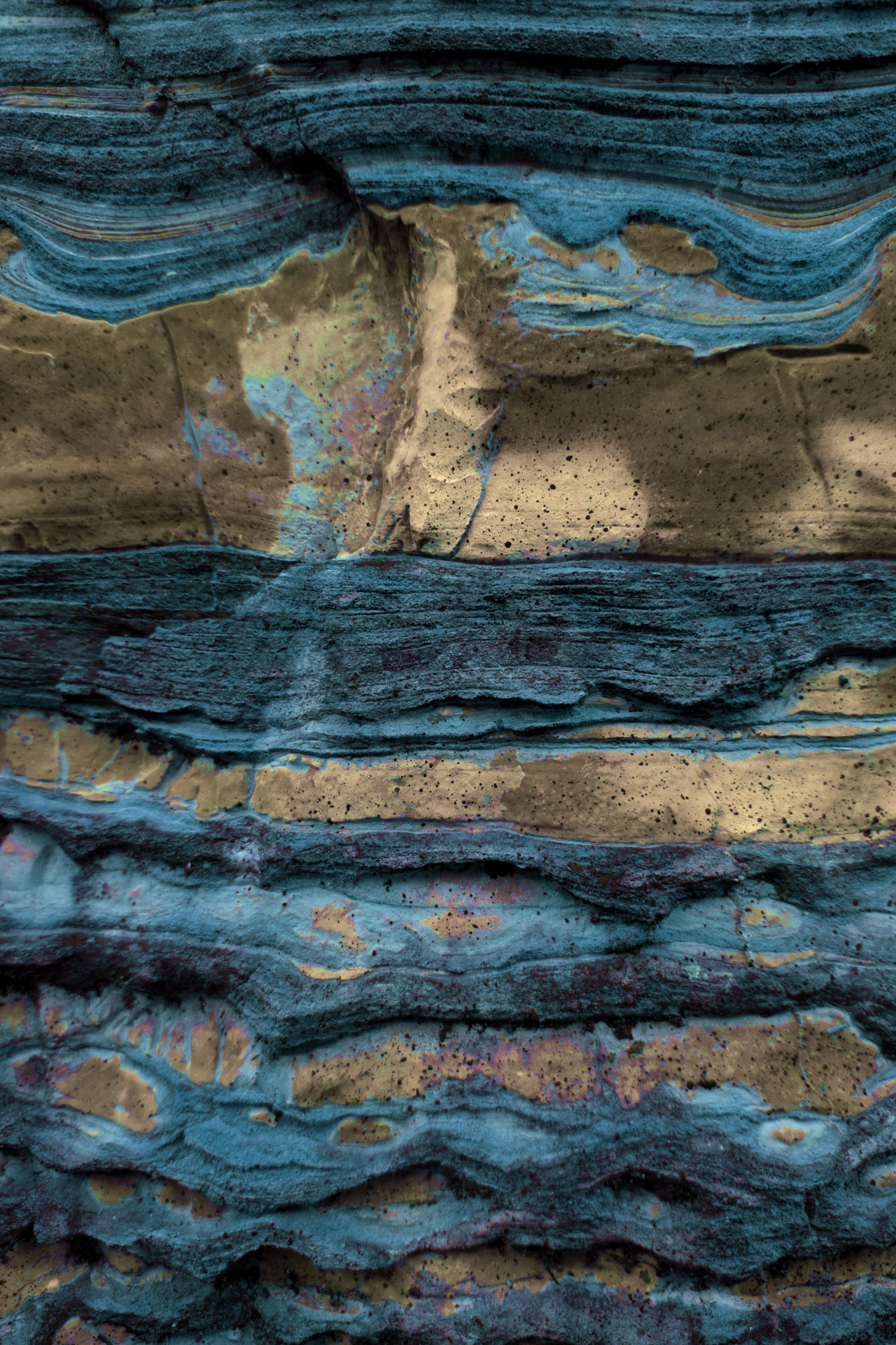 Close-up of layered rock with blue and tan colors.