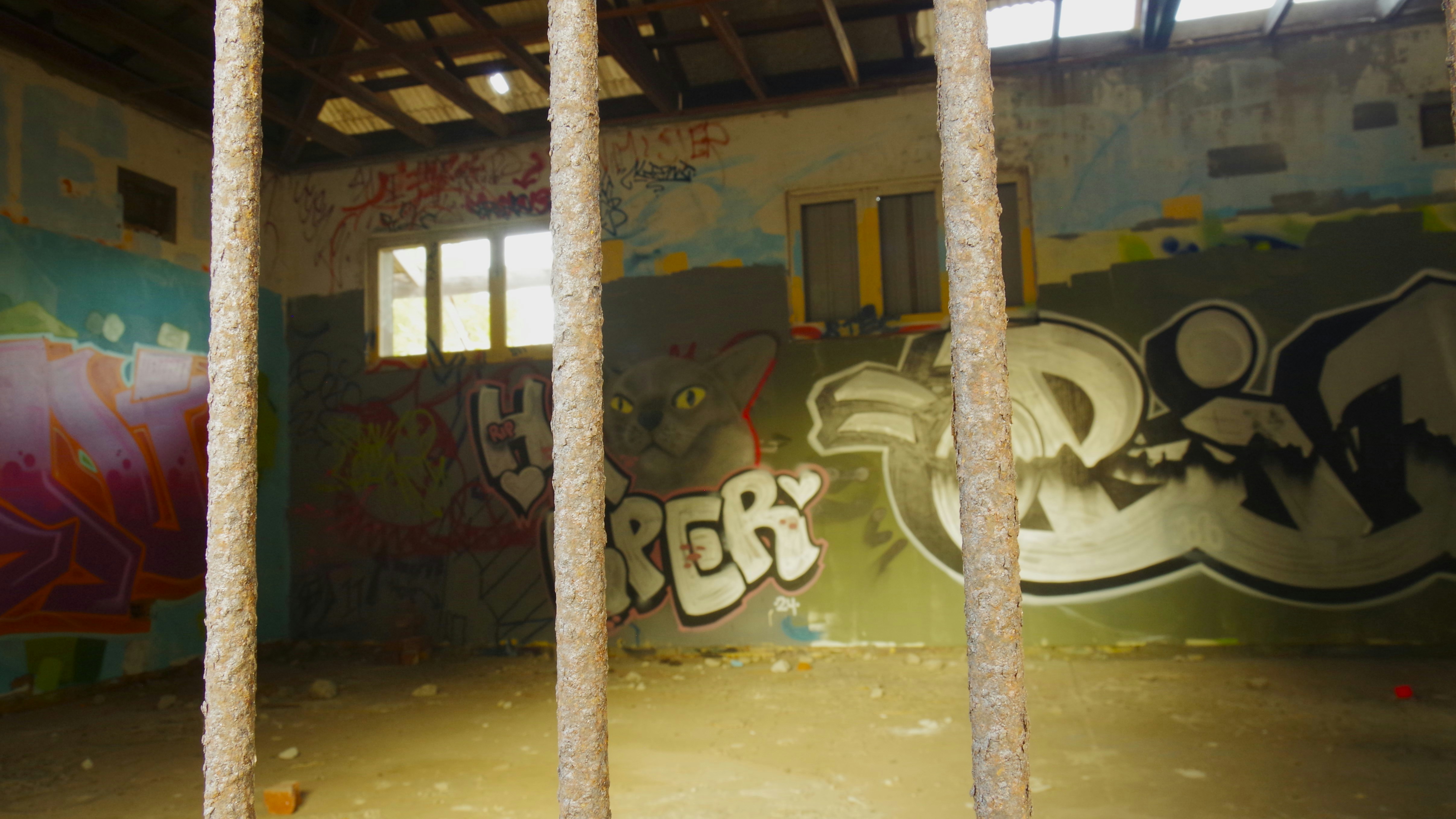 Abandoned building interior with graffiti and rusty bars.