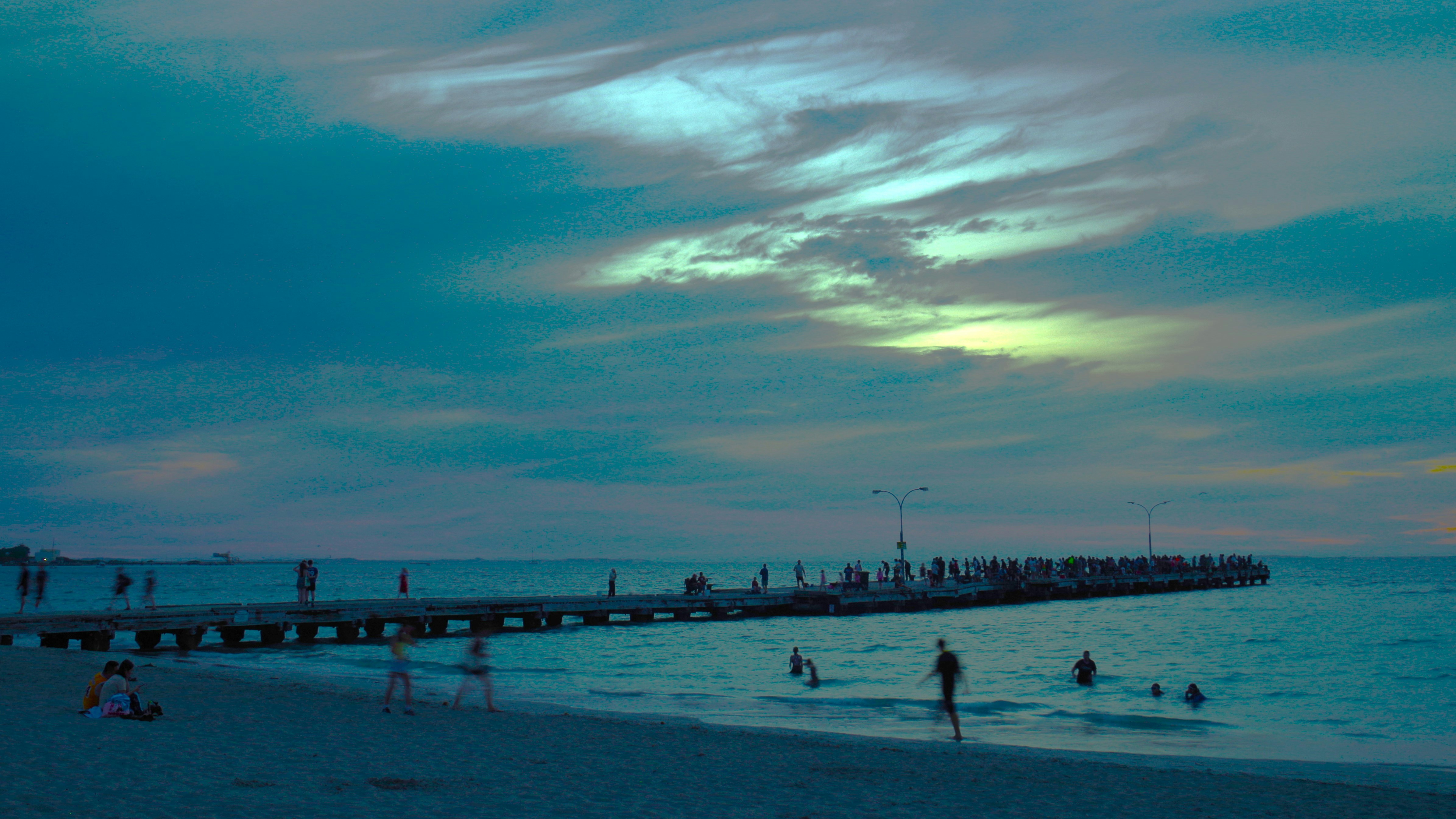 Persone su un molo al tramonto sull'oceano.