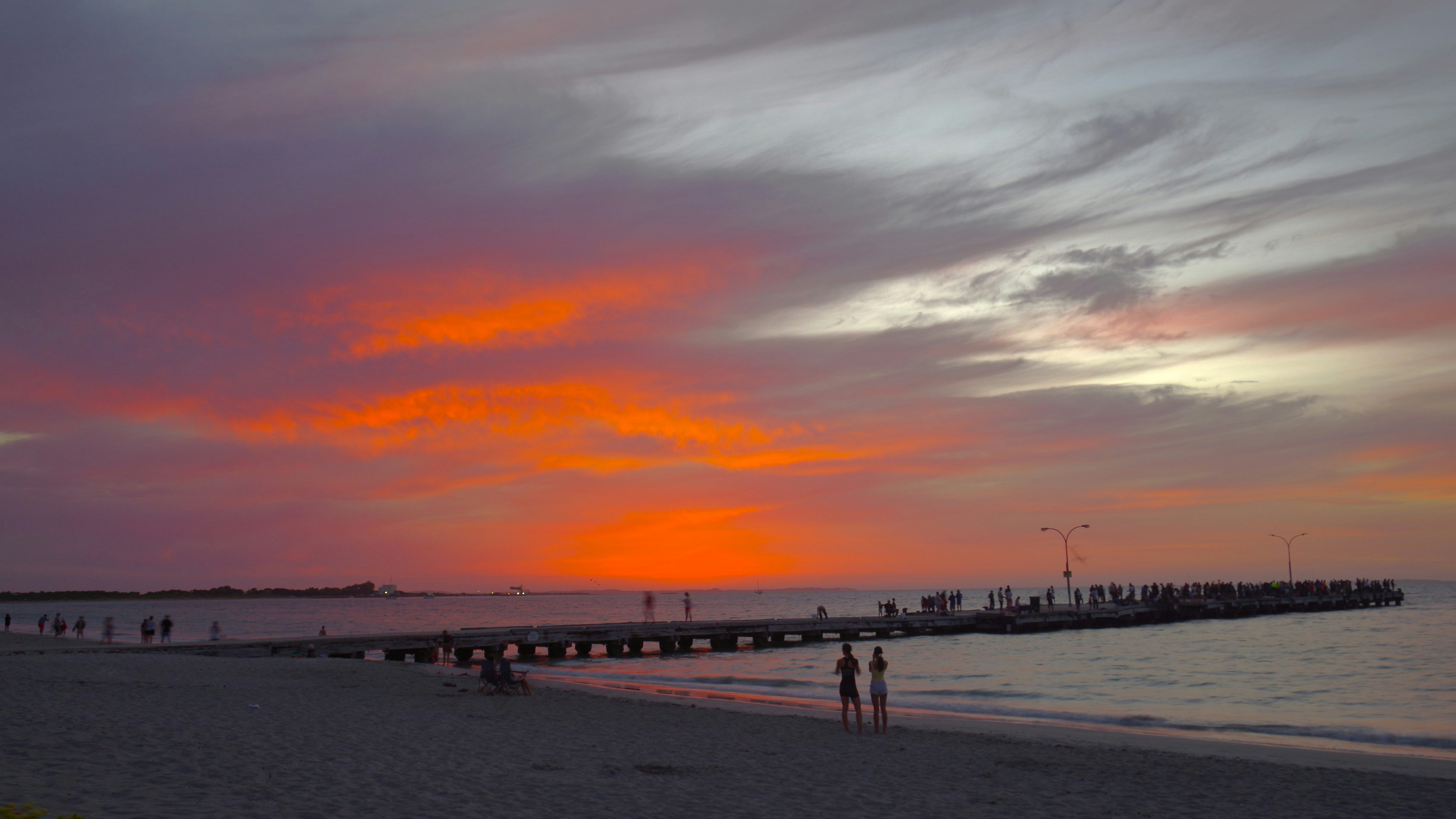 Tramonto vibrante su un molo con persone che camminano