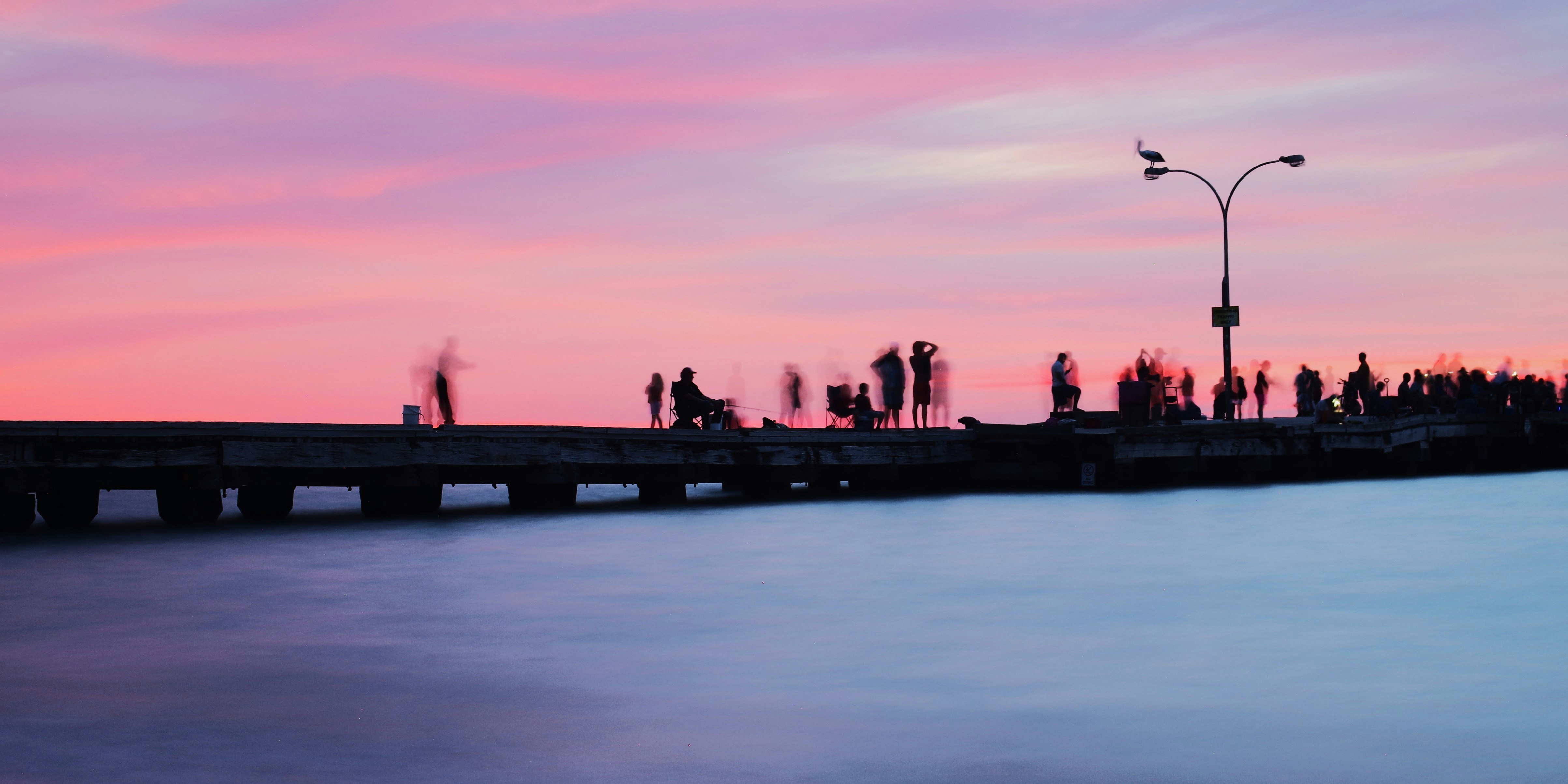 Silhouette di persone su un molo al tramonto