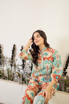 Woman in patterned clothing sitting near plants
