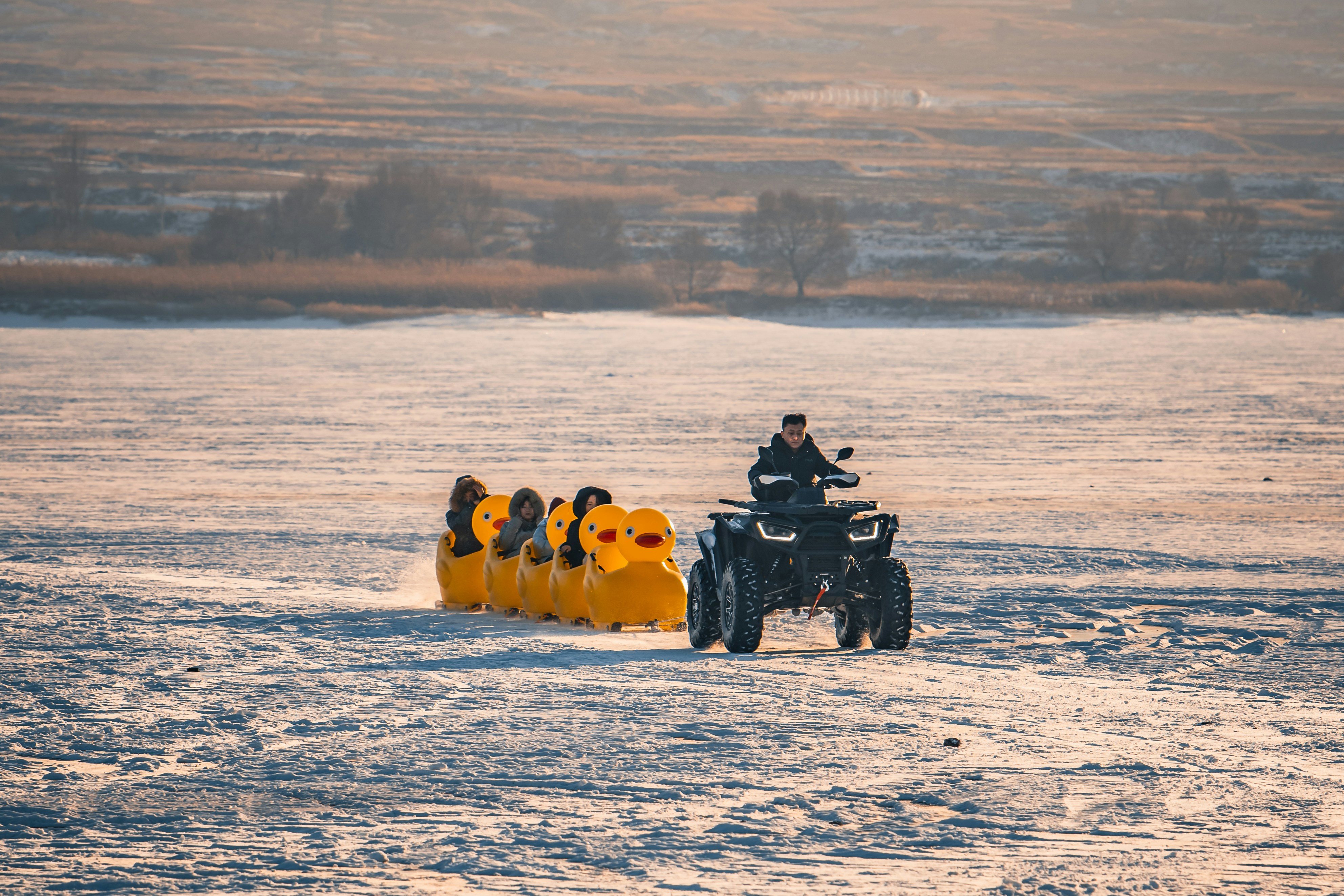 Atv towing a yellow inflatable sled on snow