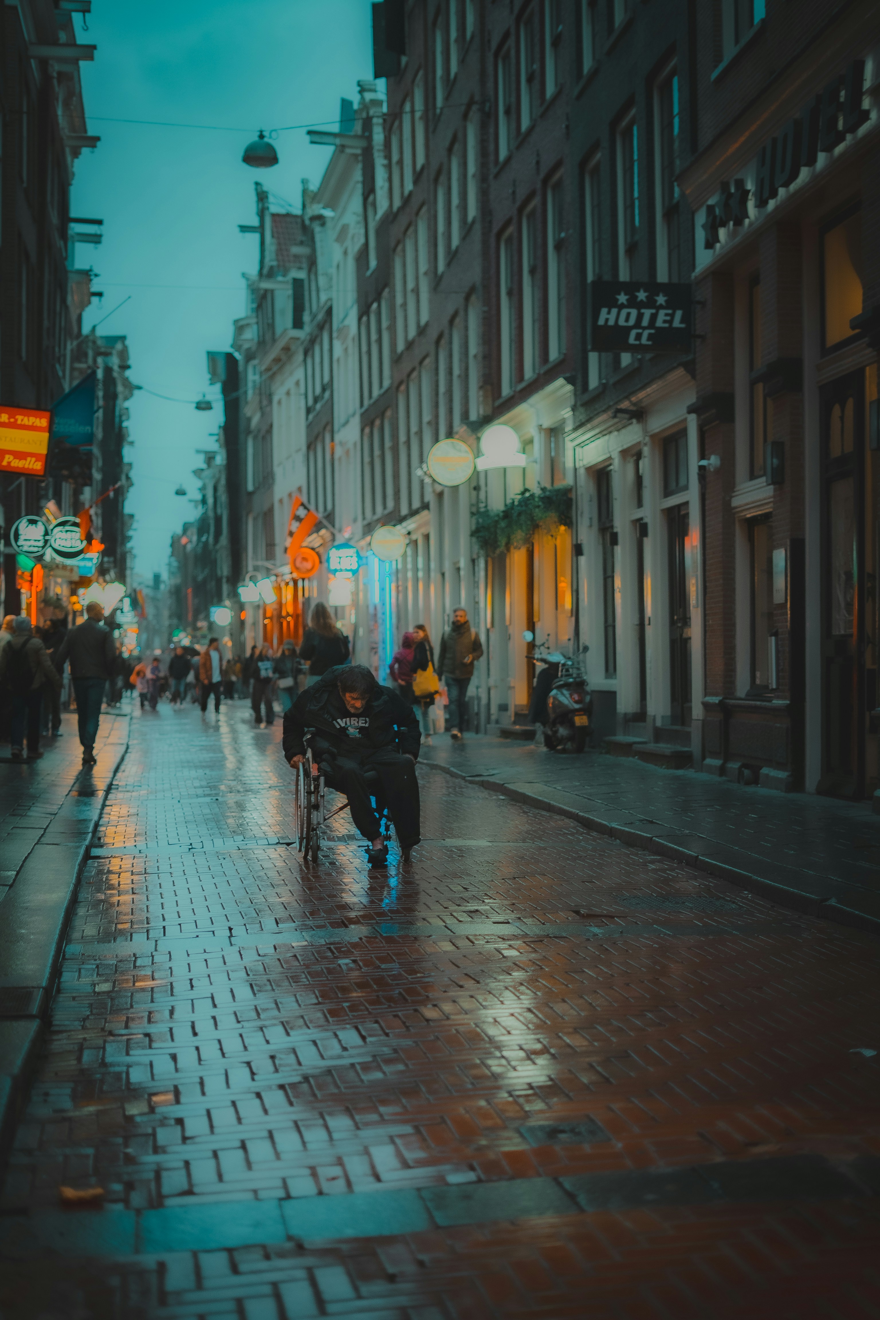 Uma pessoa em cadeira de rodas em uma rua molhada da cidade.