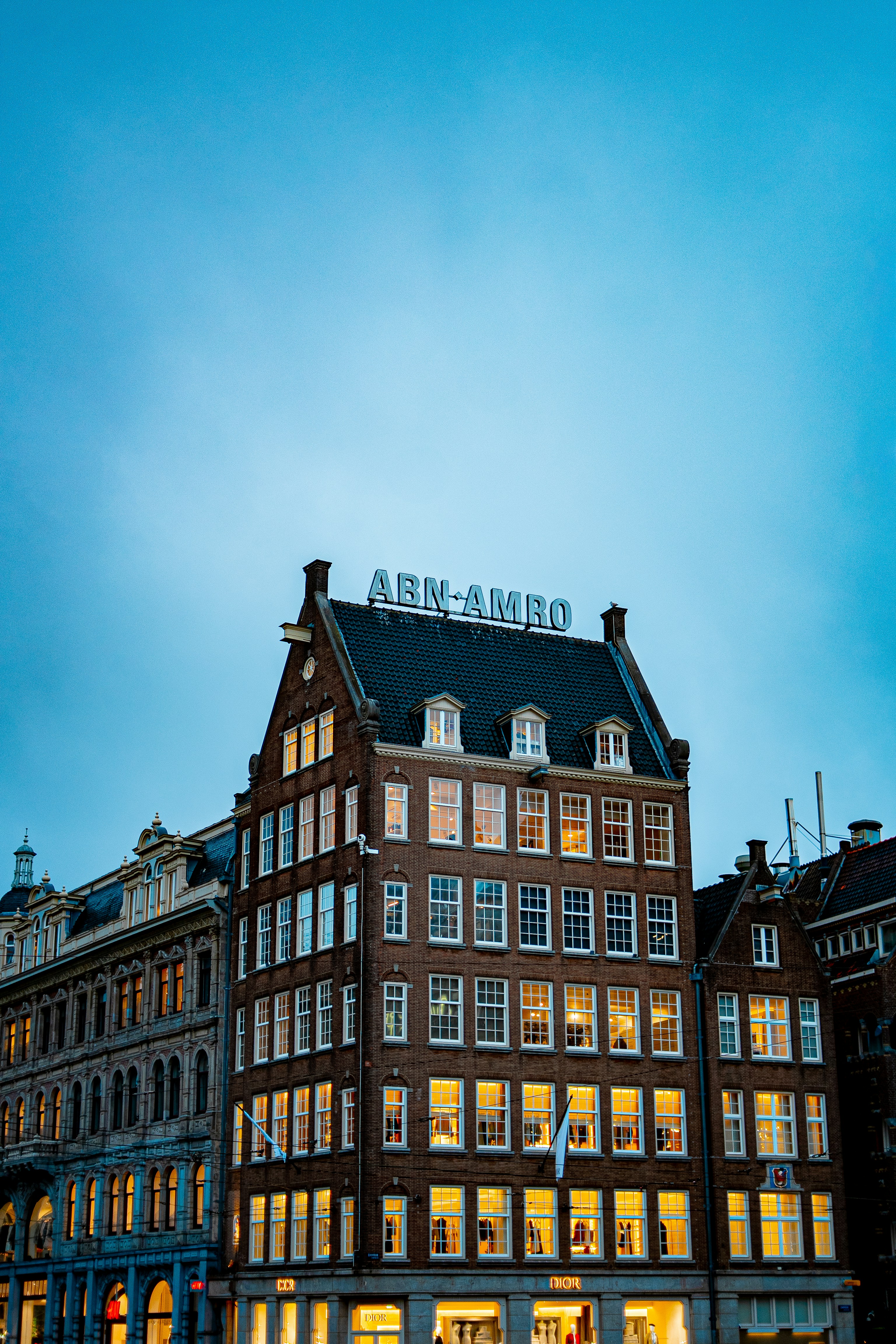 Prédio histórico de tijolos com placa de Abn Amro ao entardecer.