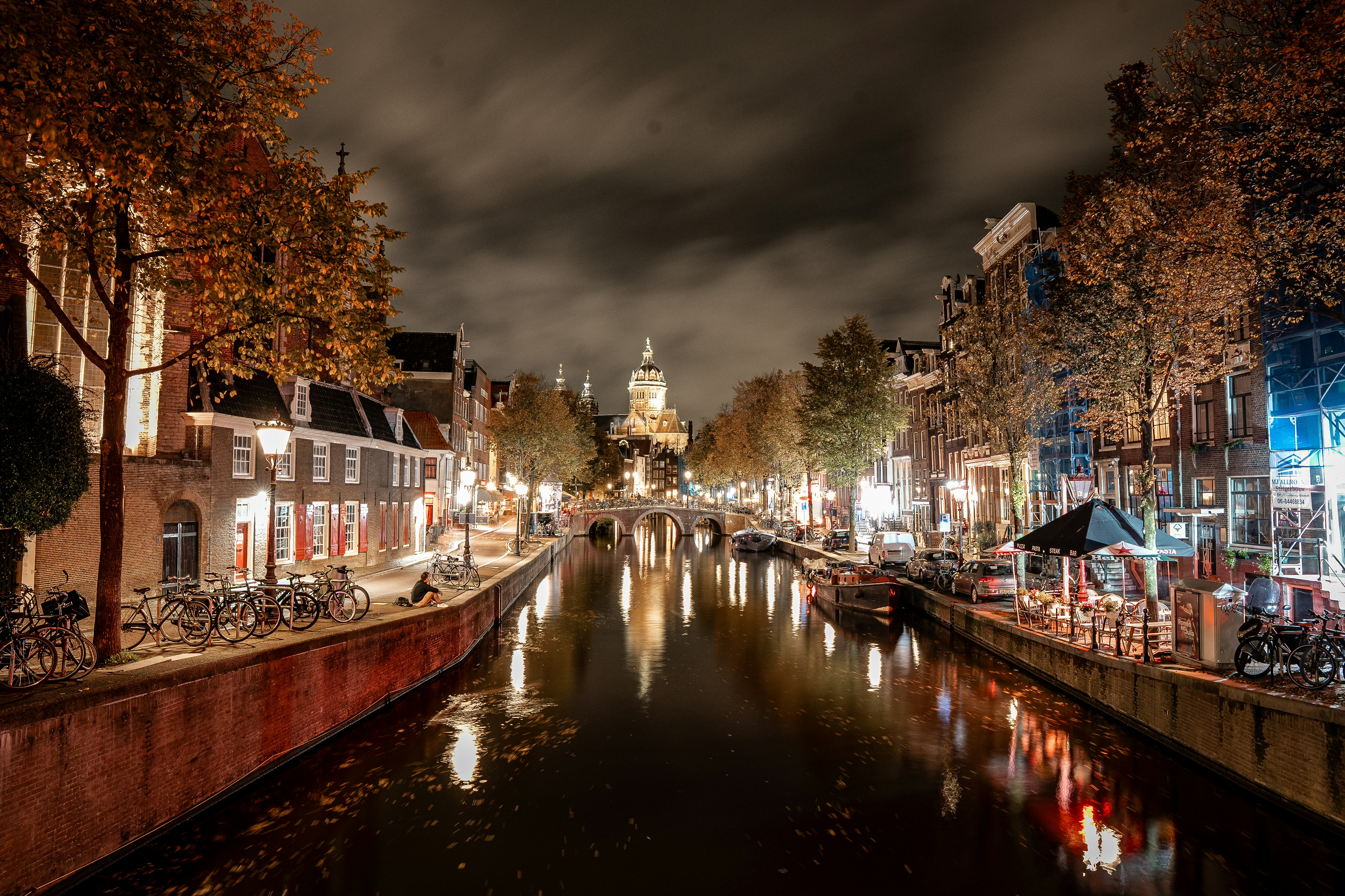 Canal da cidade à noite, com prédios e árvores iluminados.